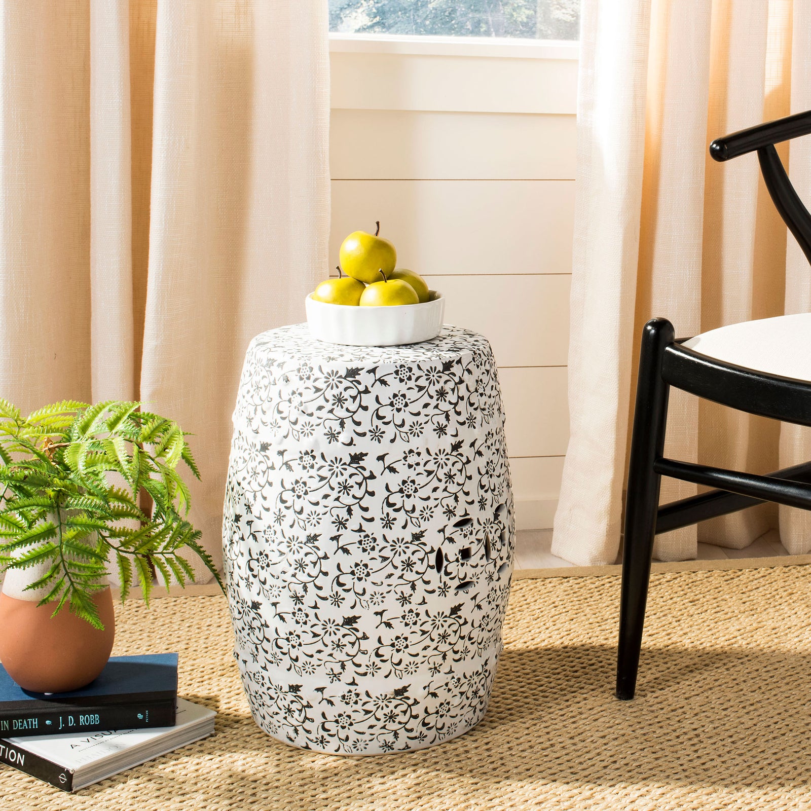 A white ceramic garden stool with floral vines serves as a decorative side table. || ACS4511A || front_angle_room