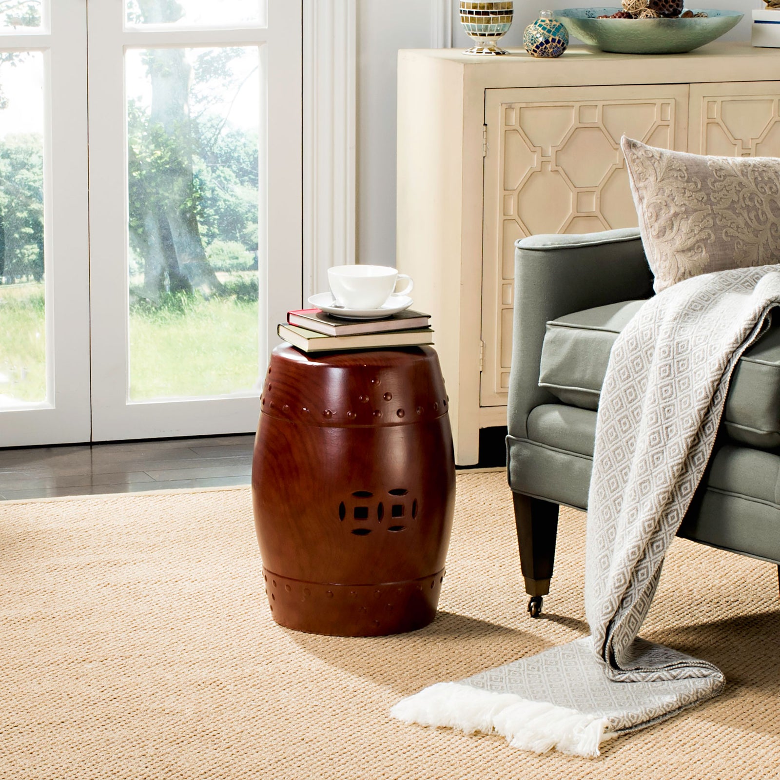 A glossy deep red ceramic stool with decorative cutouts doubles as a side table beside the sofa. || ACS4552C || front_room