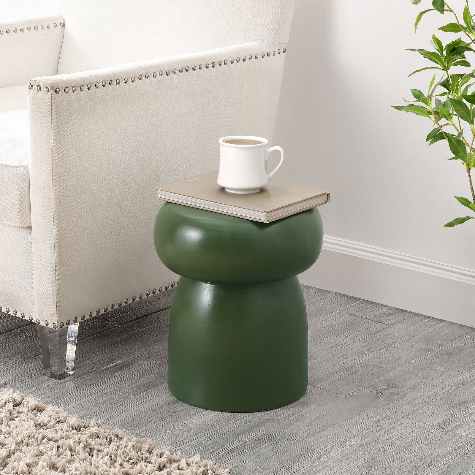 A moss green ceramic stool brings a sculptural side-table accent to a cozy seating area. || ACS4598C || front_room