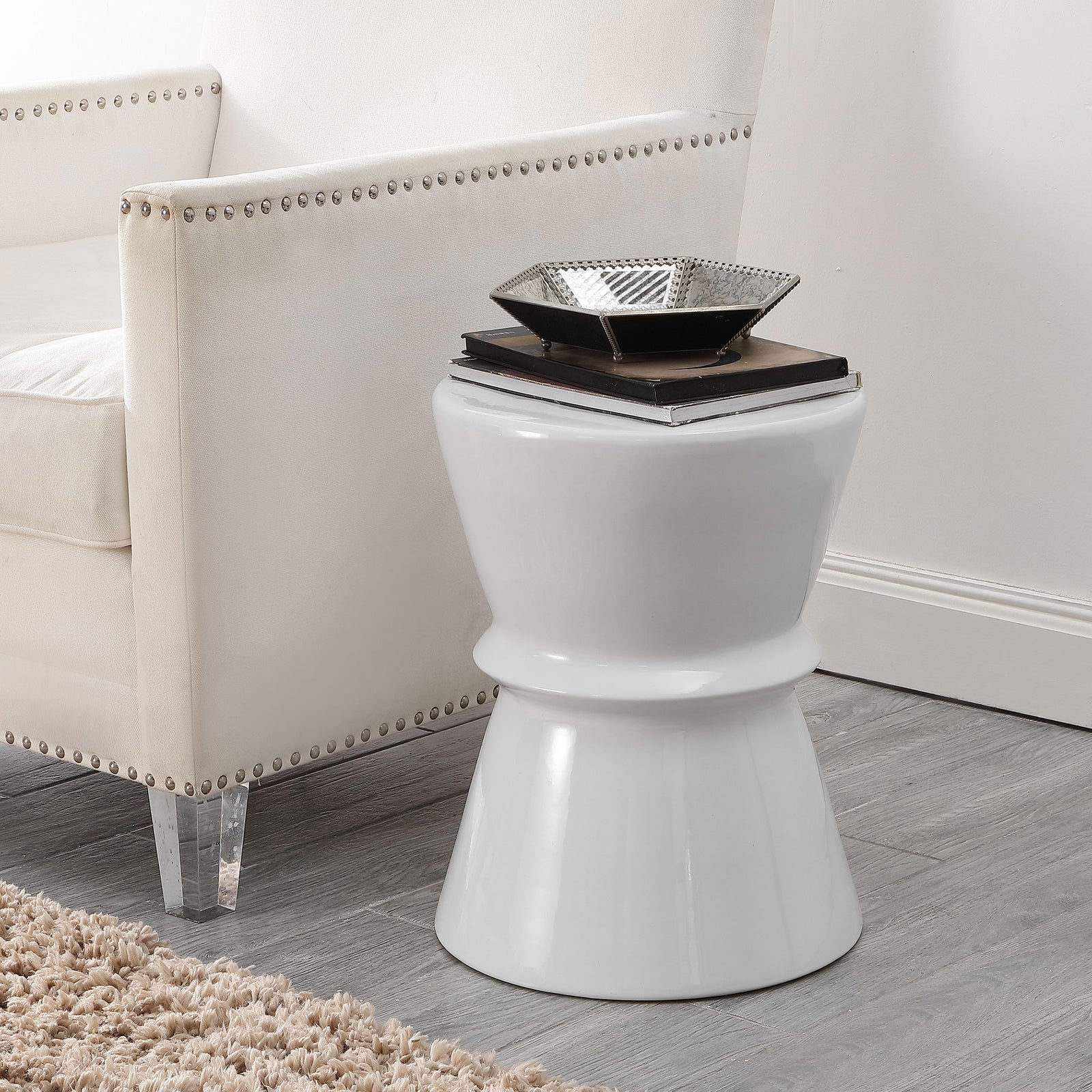 A white ceramic stool doubles as an accent table beside an upholstered chair. || ACS4601A || front_room