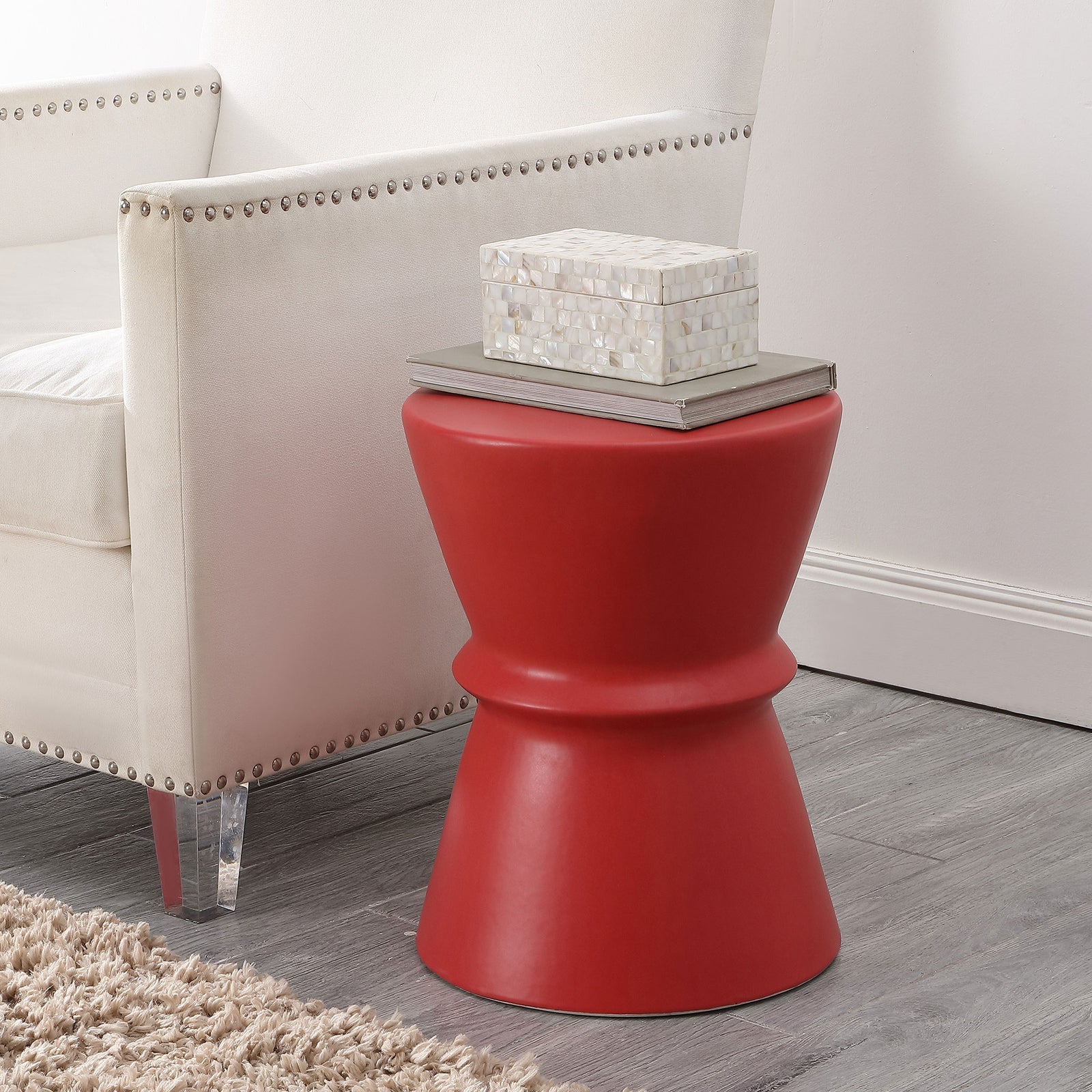 A bright red ceramic stool serves as a side table beside a light upholstered chair. || ACS4601C || front_room