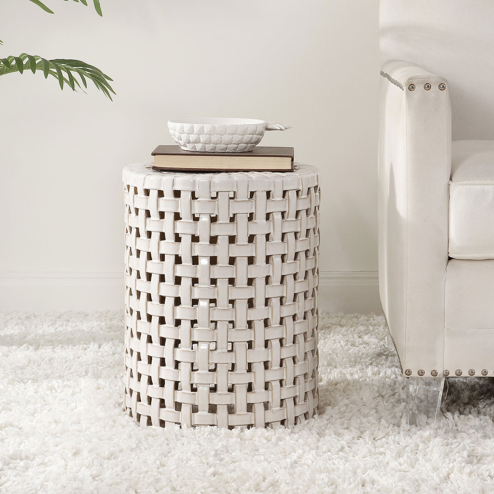 Cream ceramic stool with airy latticework holds books beside a sofa || ACS4606A || front_room