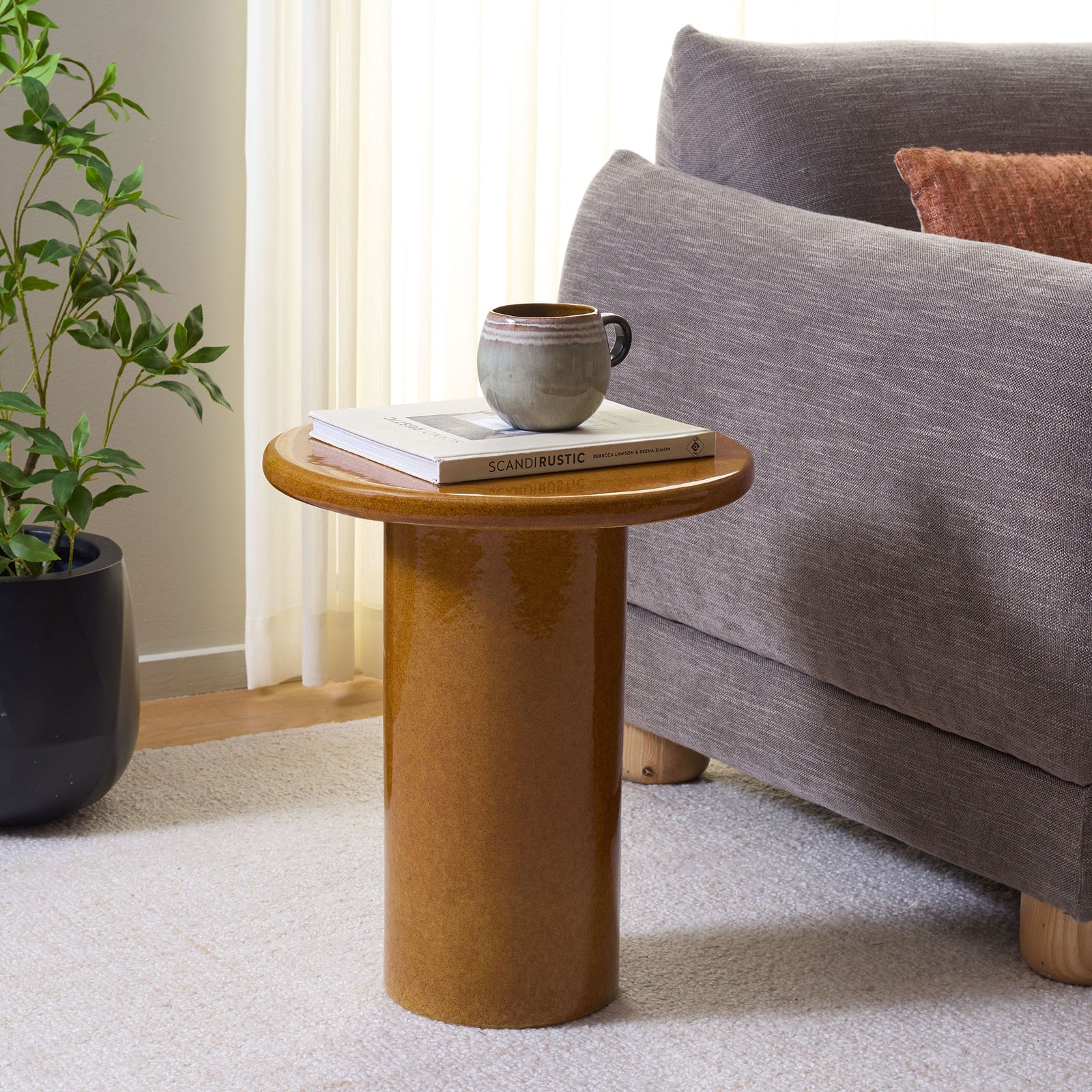Ginger ceramic stool serves as a side table for books and a mug beside the sofa || ACS4610A || front_angle_room