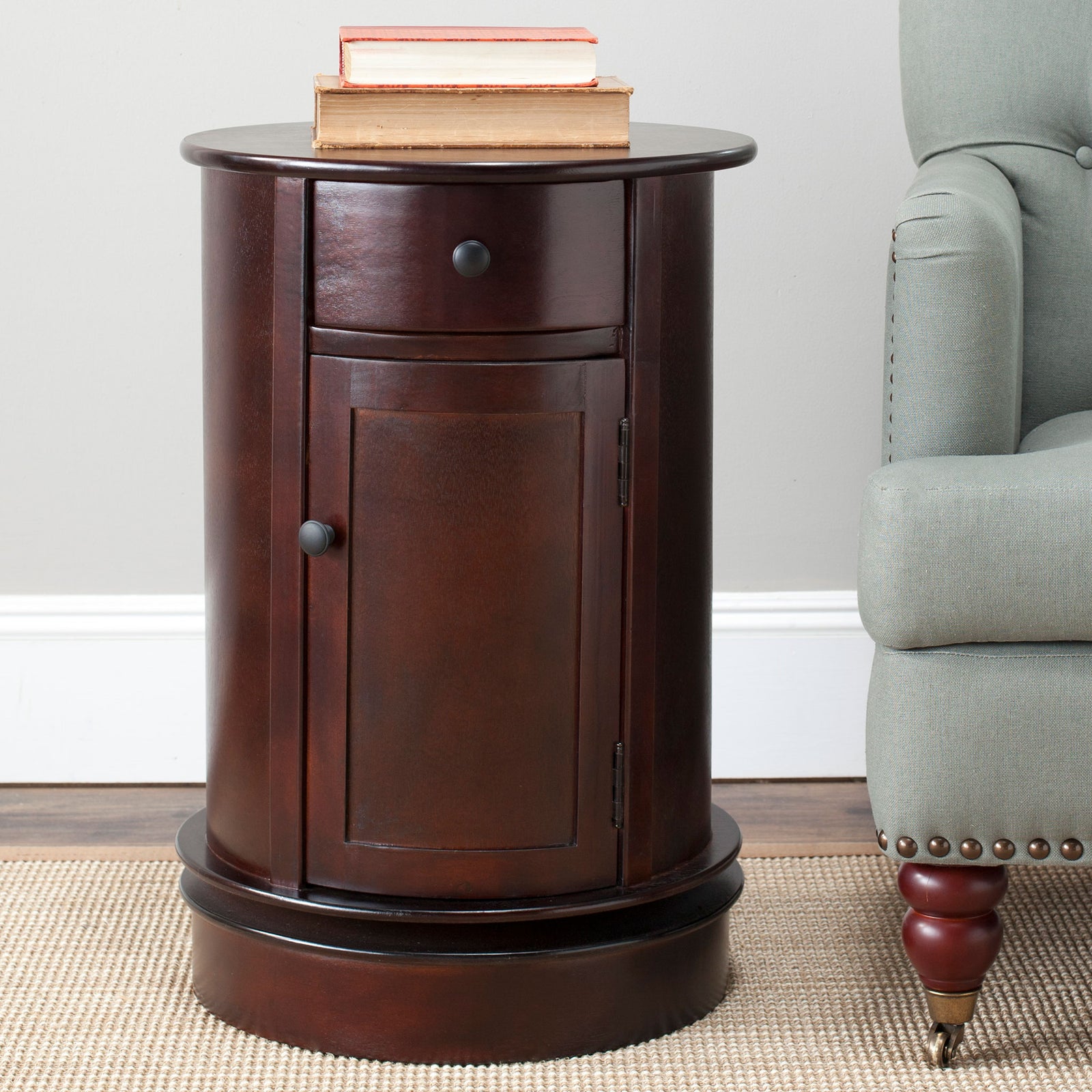 A round dark cherry tabletop holds books above a compact storage cabinet || AMH5712D || front_room