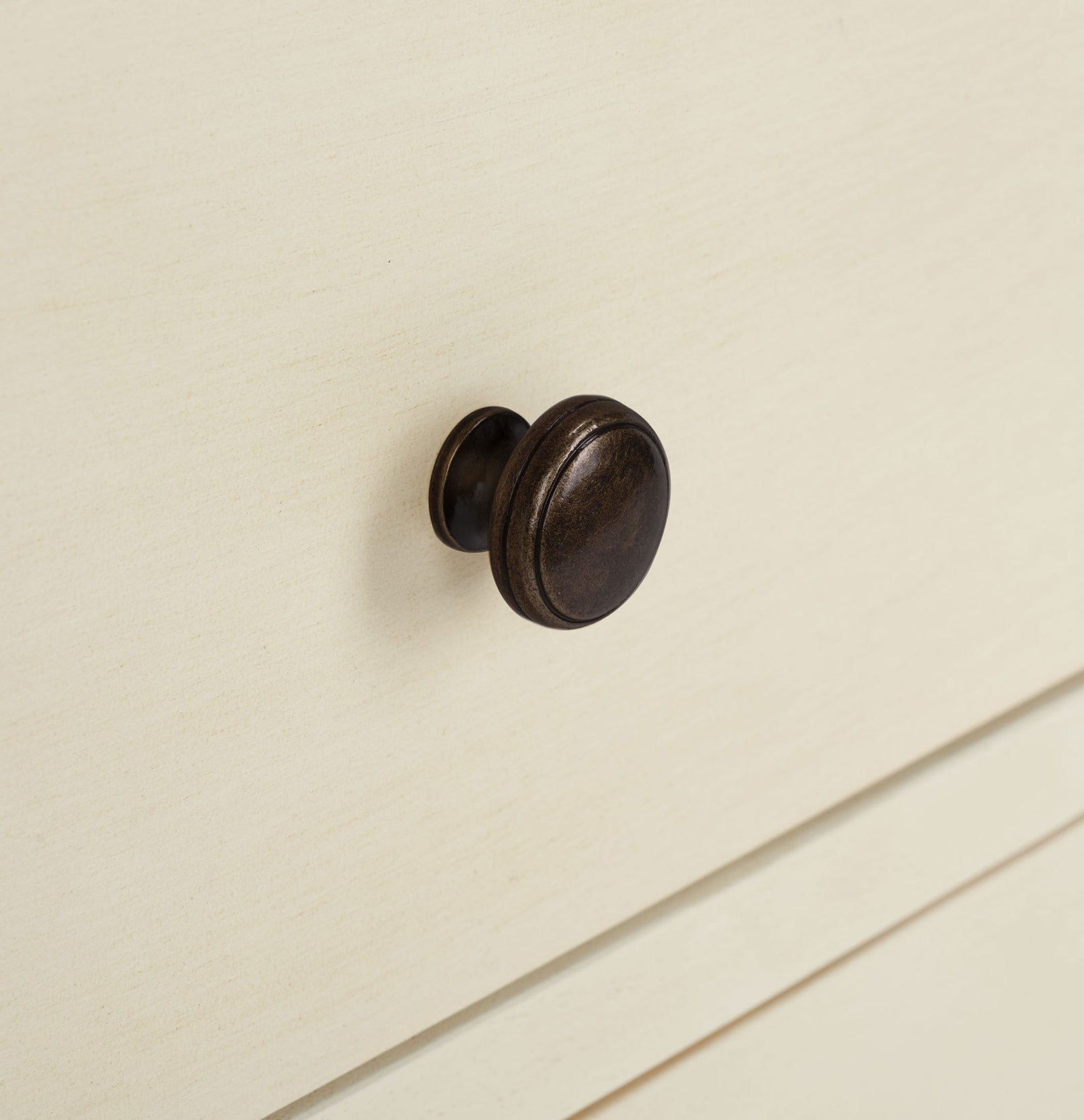 A dark bronze knob stands out against the creamy, softly distressed drawer front. || AMH6629D || handle_studio