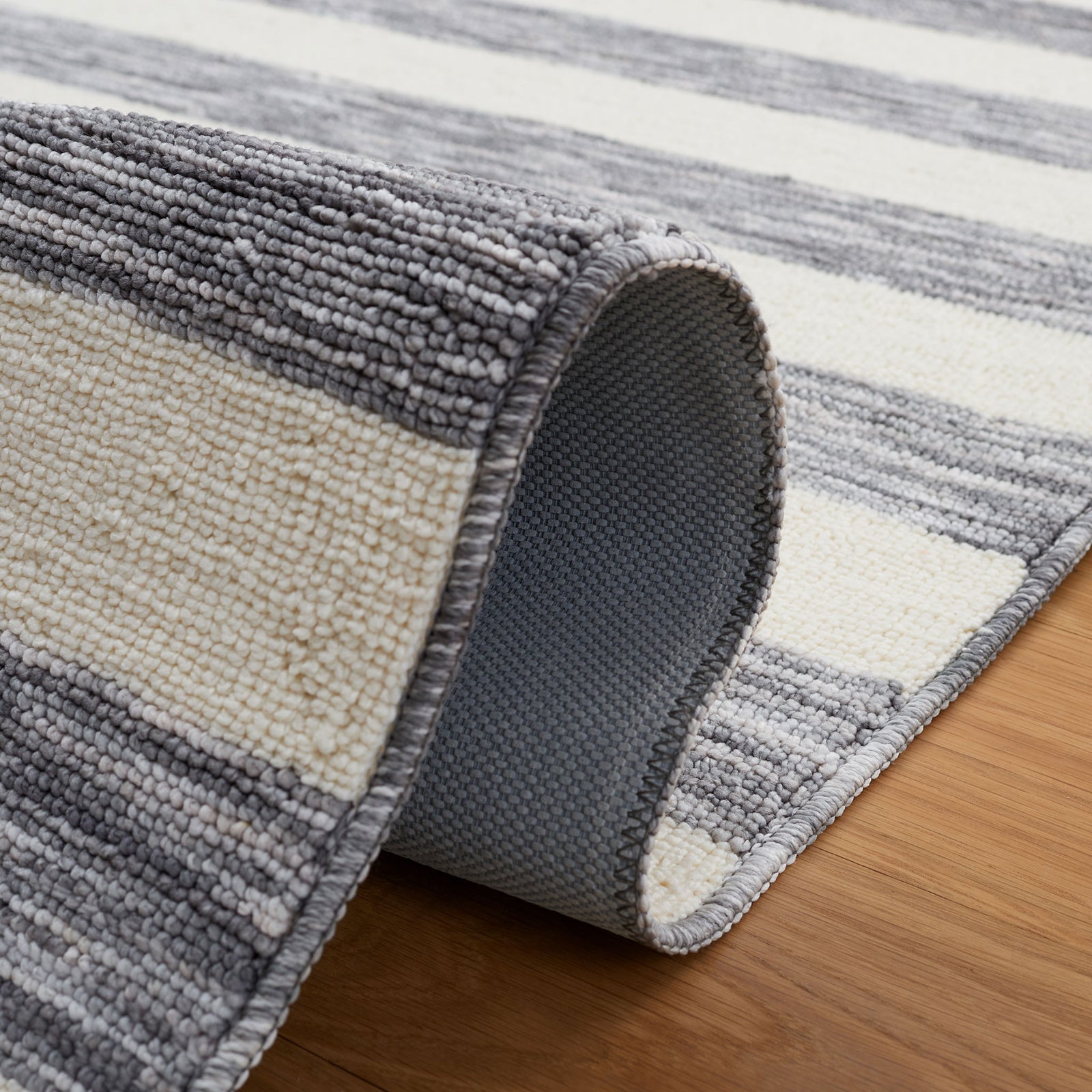 Flexible rug reveals latex backing and textured, heathered gray-and-ivory stripes || ECR115H-5 || fold_room