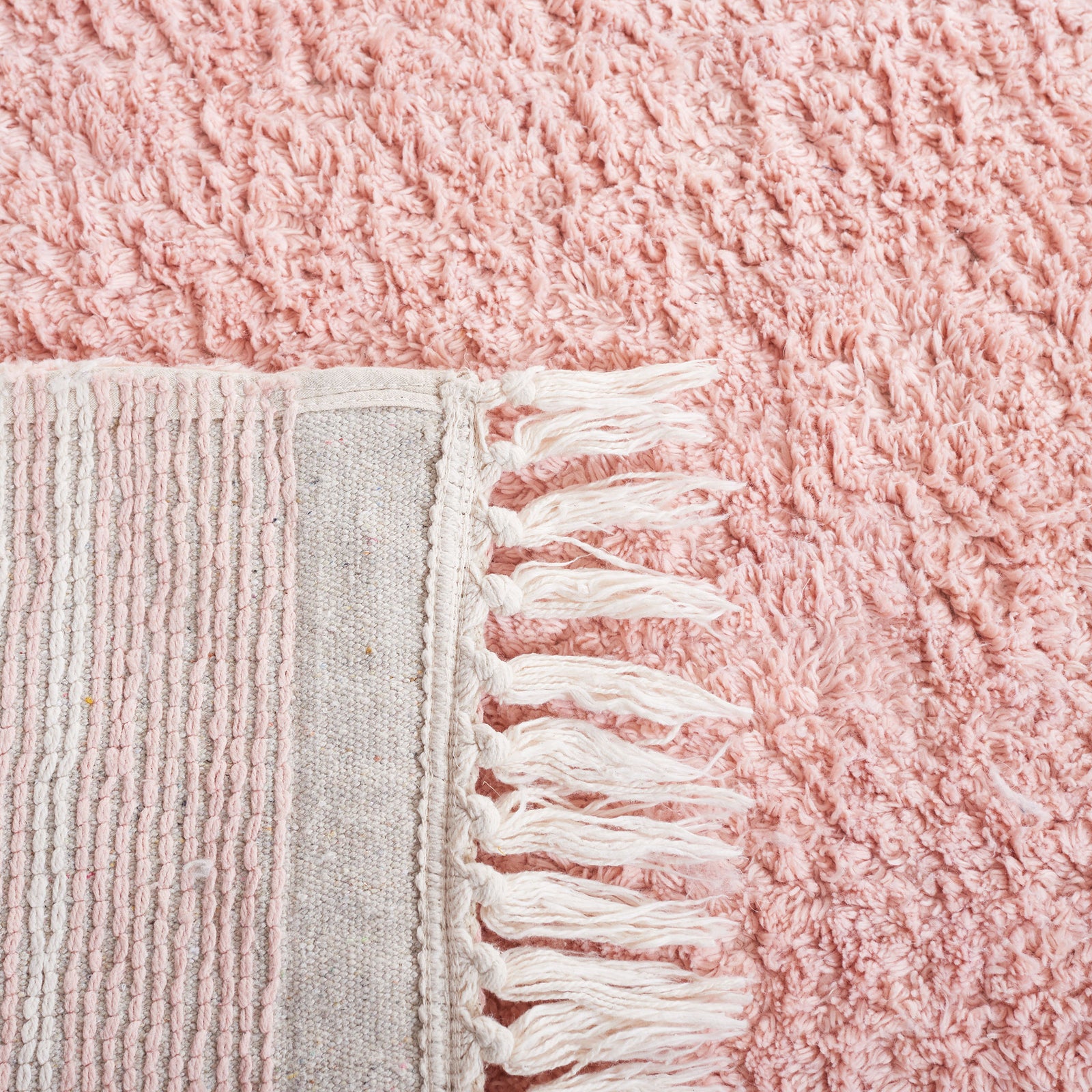 A flipped edge reveals the durable woven backing and neat ivory fringe on the pink pile. || ECR211U-5 || backing_room
