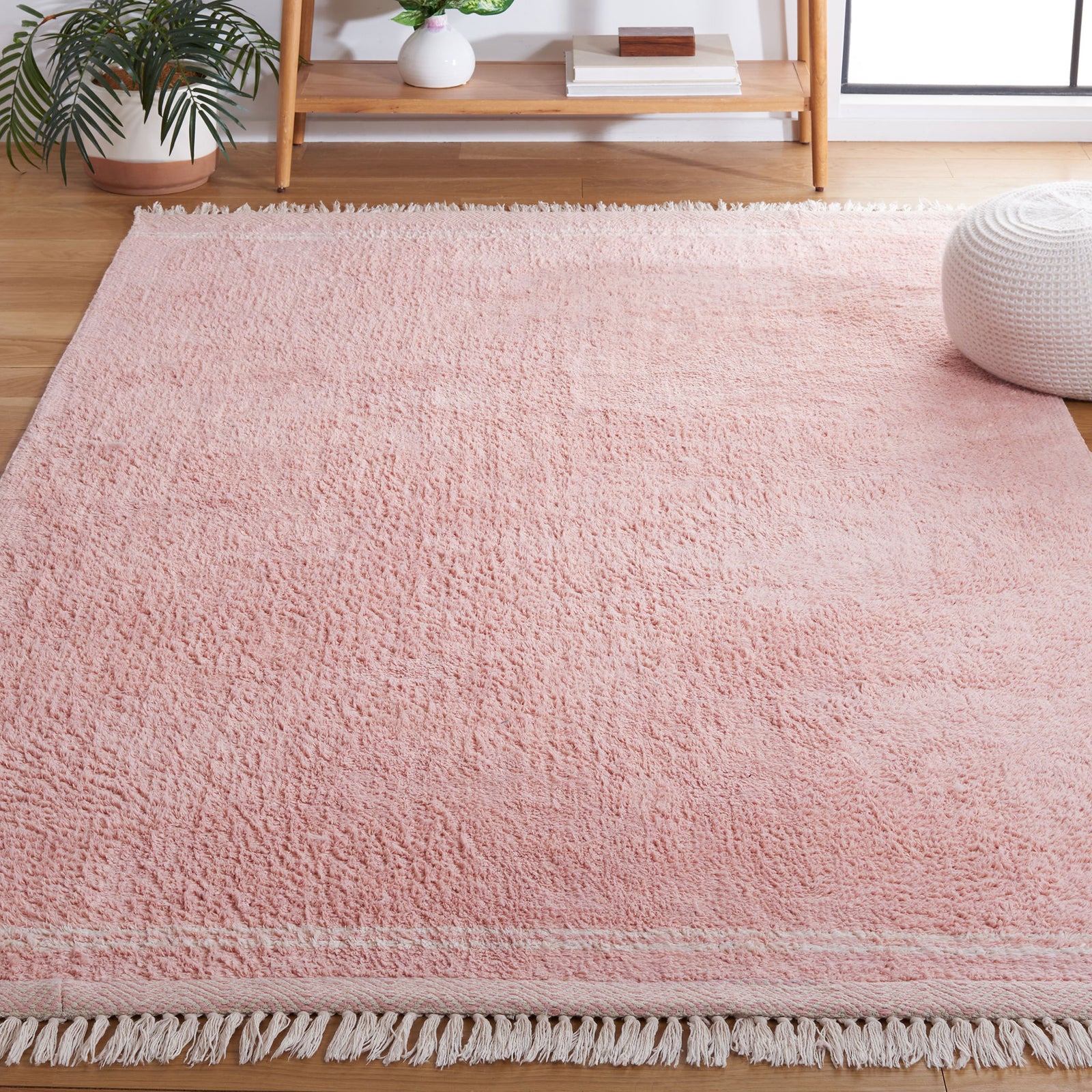 Soft pink rug brings warmth and texture to the living space, finished with ivory trim and tassels. || ECR211U-5 || top_angle_room