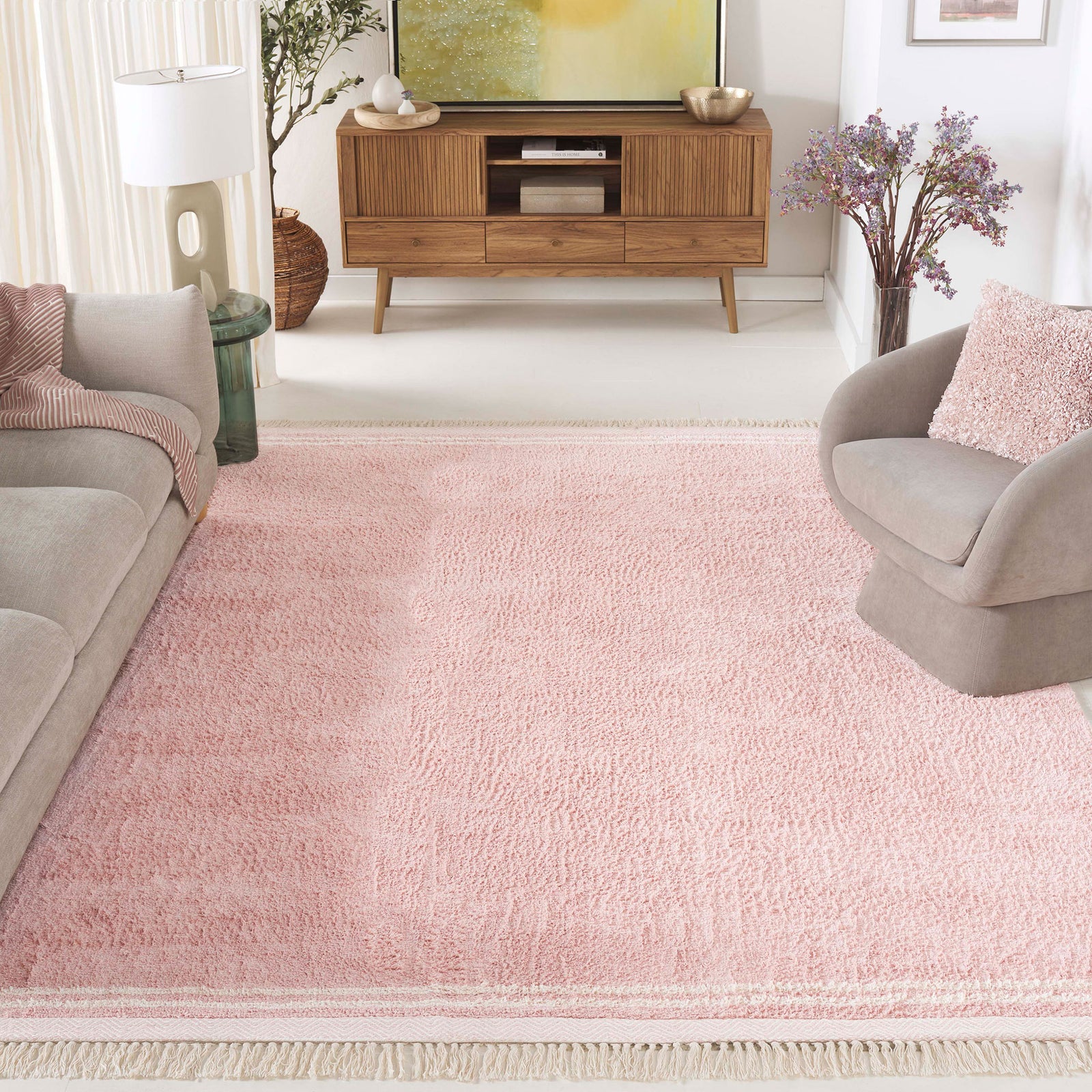 Warm pink area rug anchors the space with plush texture, ivory borders, and playful tassels. || ECR211U-8 || top_angle_room