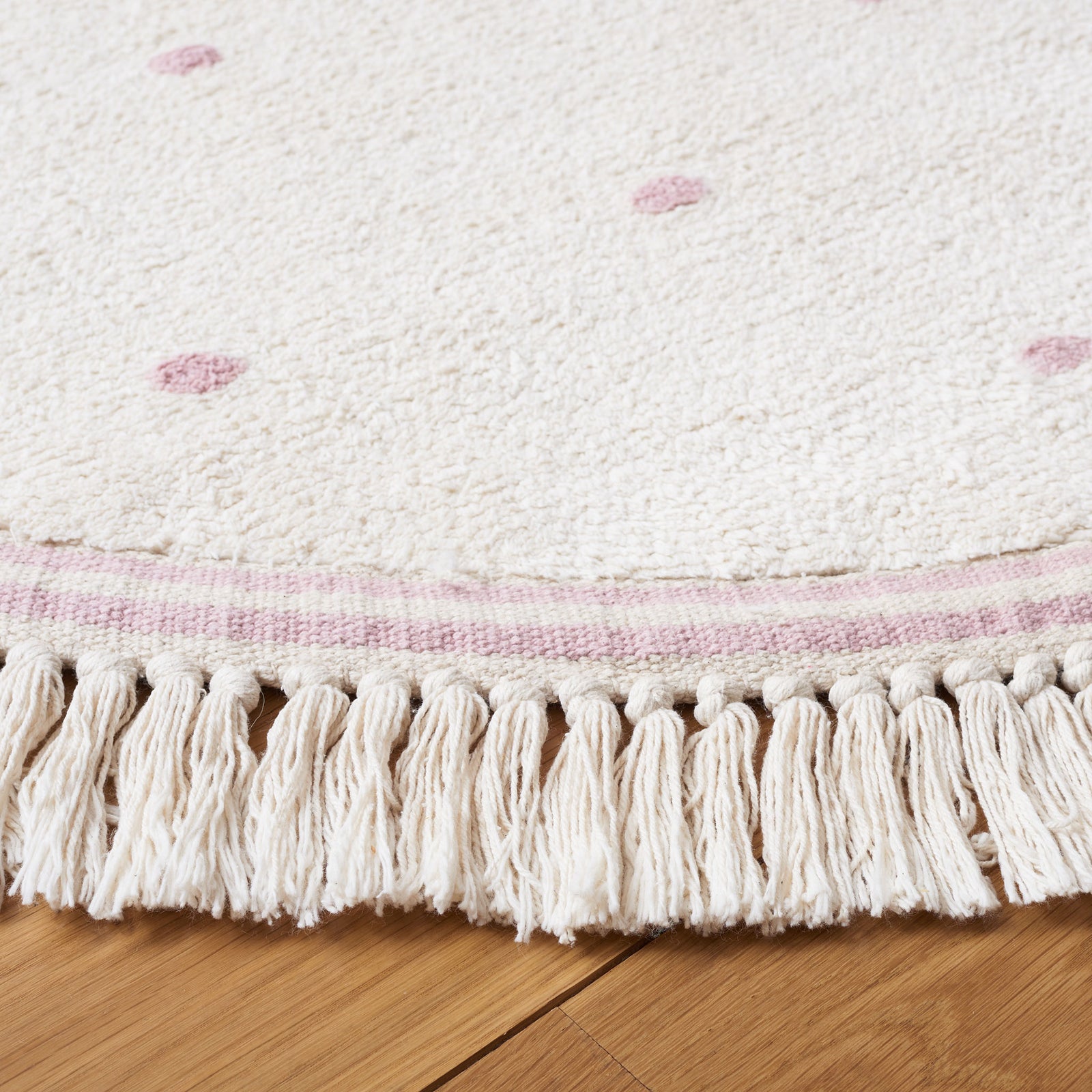Tassel fringe and soft texture highlight the ivory round rug with soft pink dots. || ECR212U-6R || detail_room