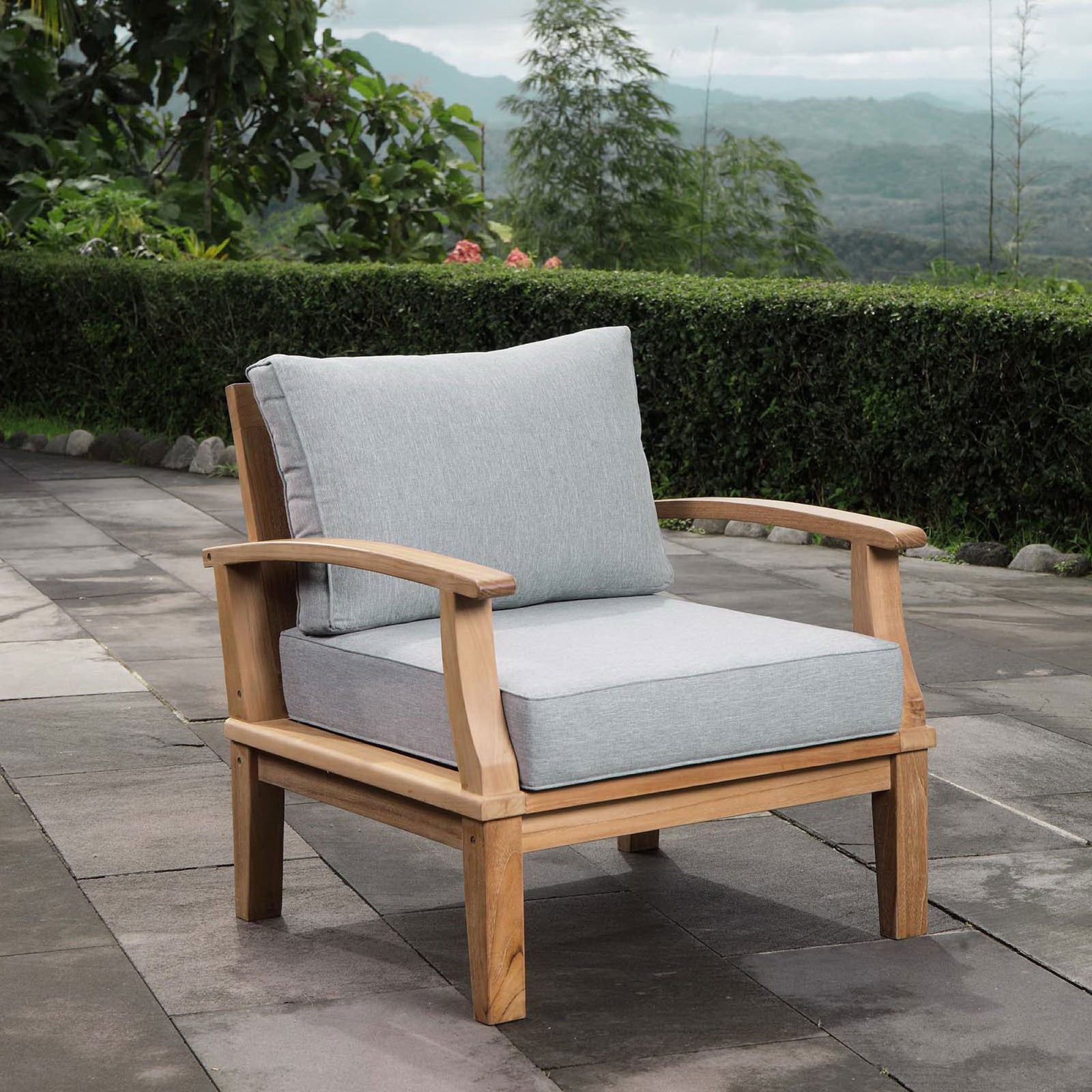 Marina teak armchair with gray cushions styled on a modern stone patio || EEI-1143-NAT-GRY-SET || front_angle_room