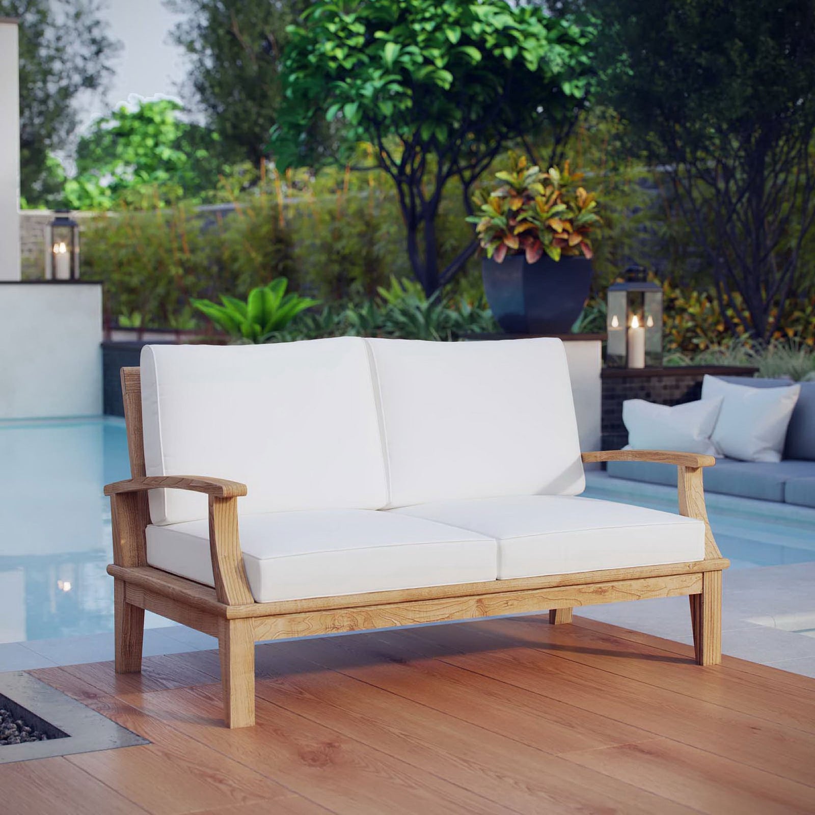 Teak loveseat with white cushions styled by a modern poolside deck surrounded by greenery || EEI-1144-NAT-WHI-SET || front_angle_room