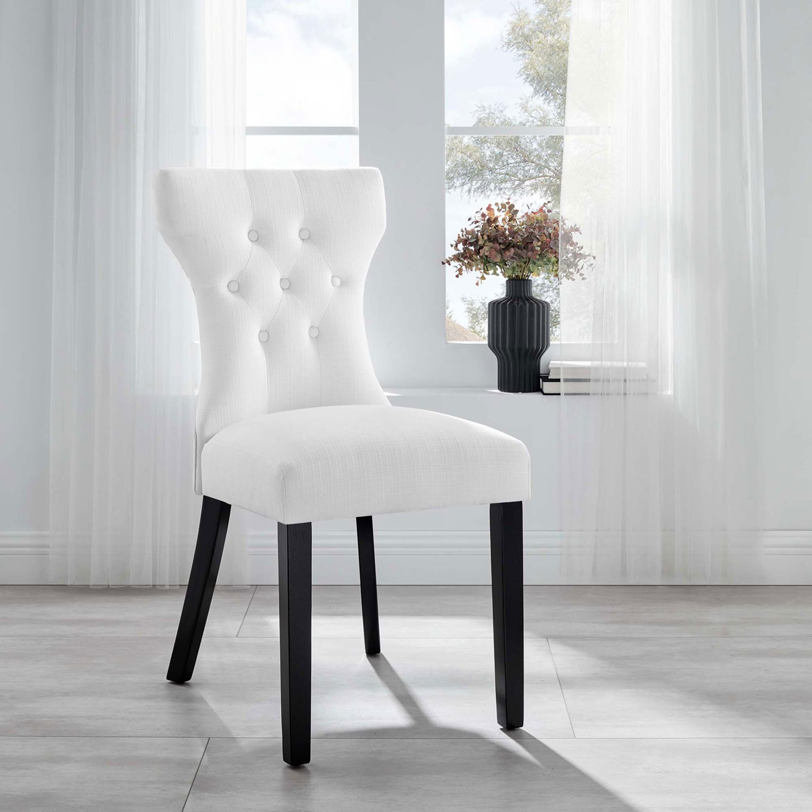 White tufted dining chair with dark legs bringing crisp contrast and texture to a bright airy room || EEI-1380-WHI || front_angle_room