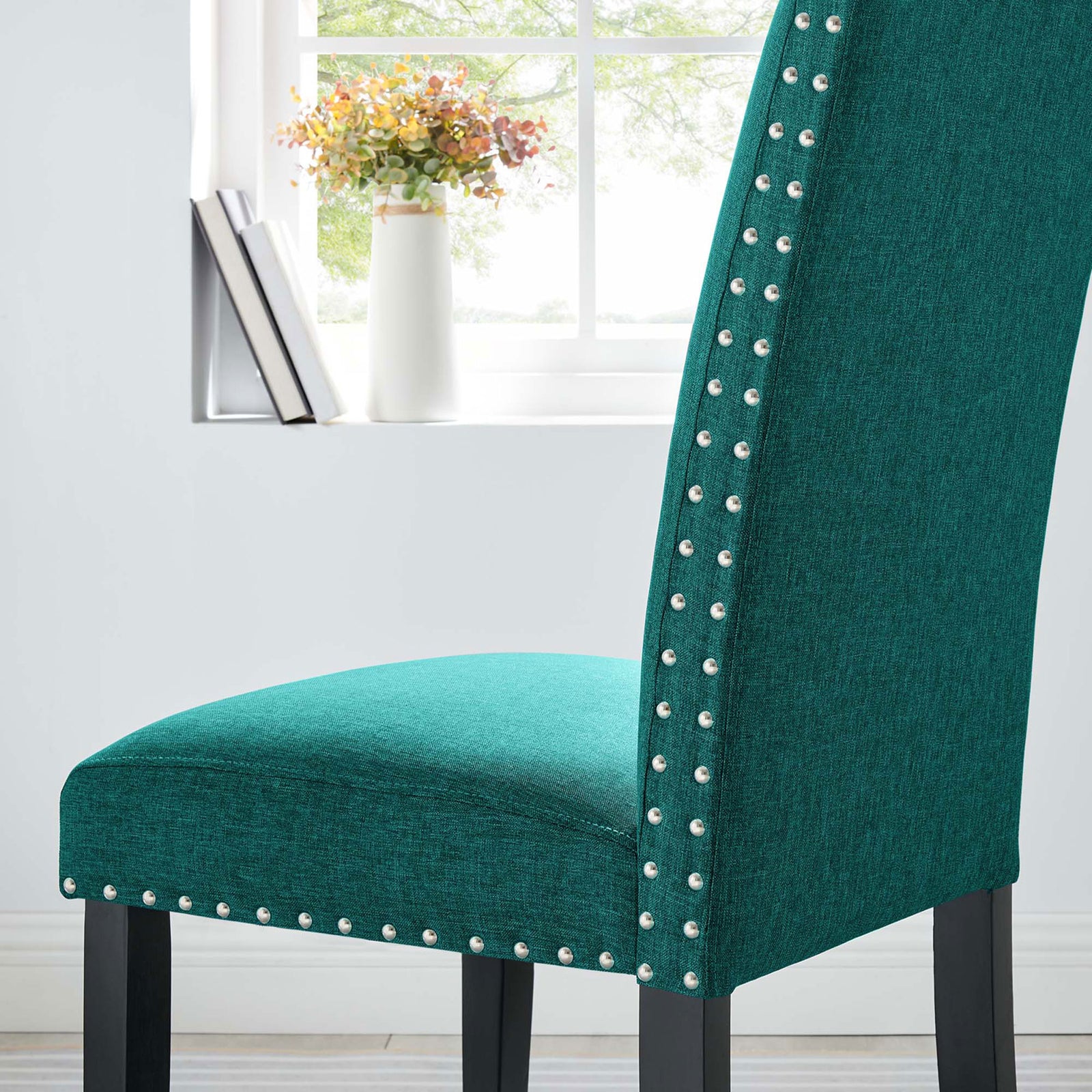 Teal dining chair beside a bright window showcasing nailhead trim and plush upholstered seating || EEI-1384-TEA || detail_room