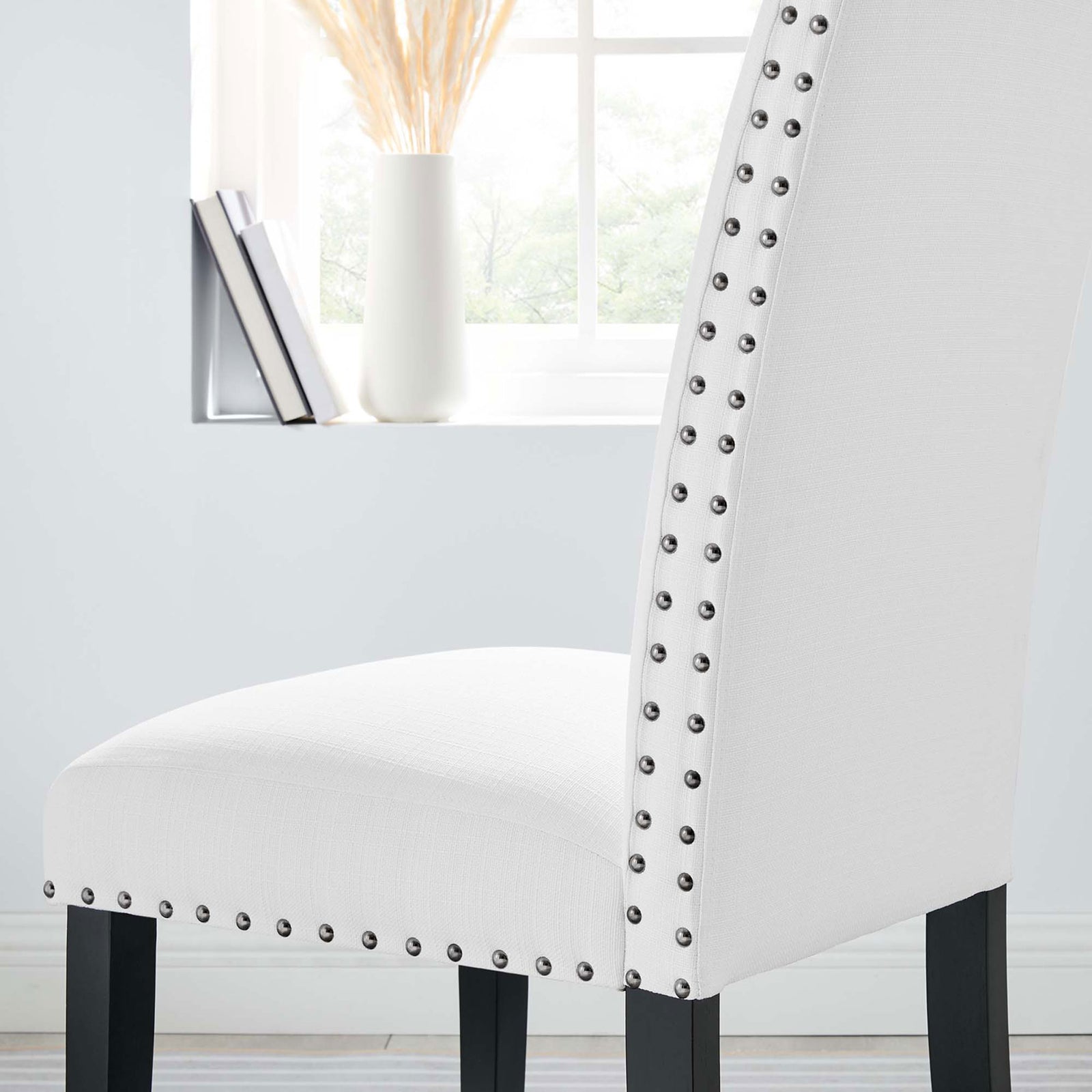 White nailhead dining chair styled in a bright room beside a sunlit window || EEI-1384-WHI || detail_room
