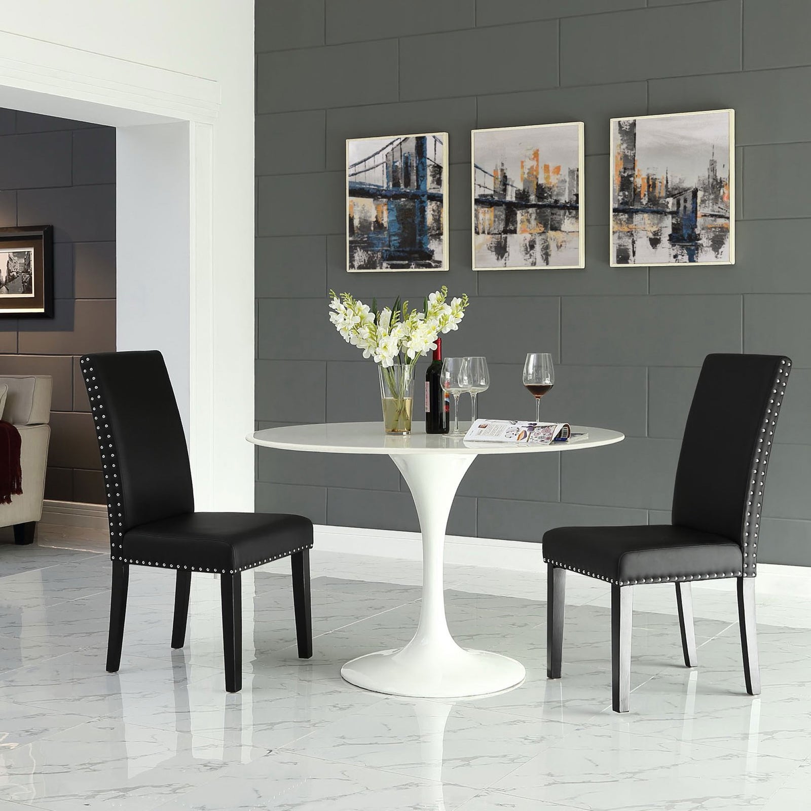 Pair of black faux leather dining chairs creating a chic contrast around a modern white pedestal table || EEI-1491-BLK || front_angle_room