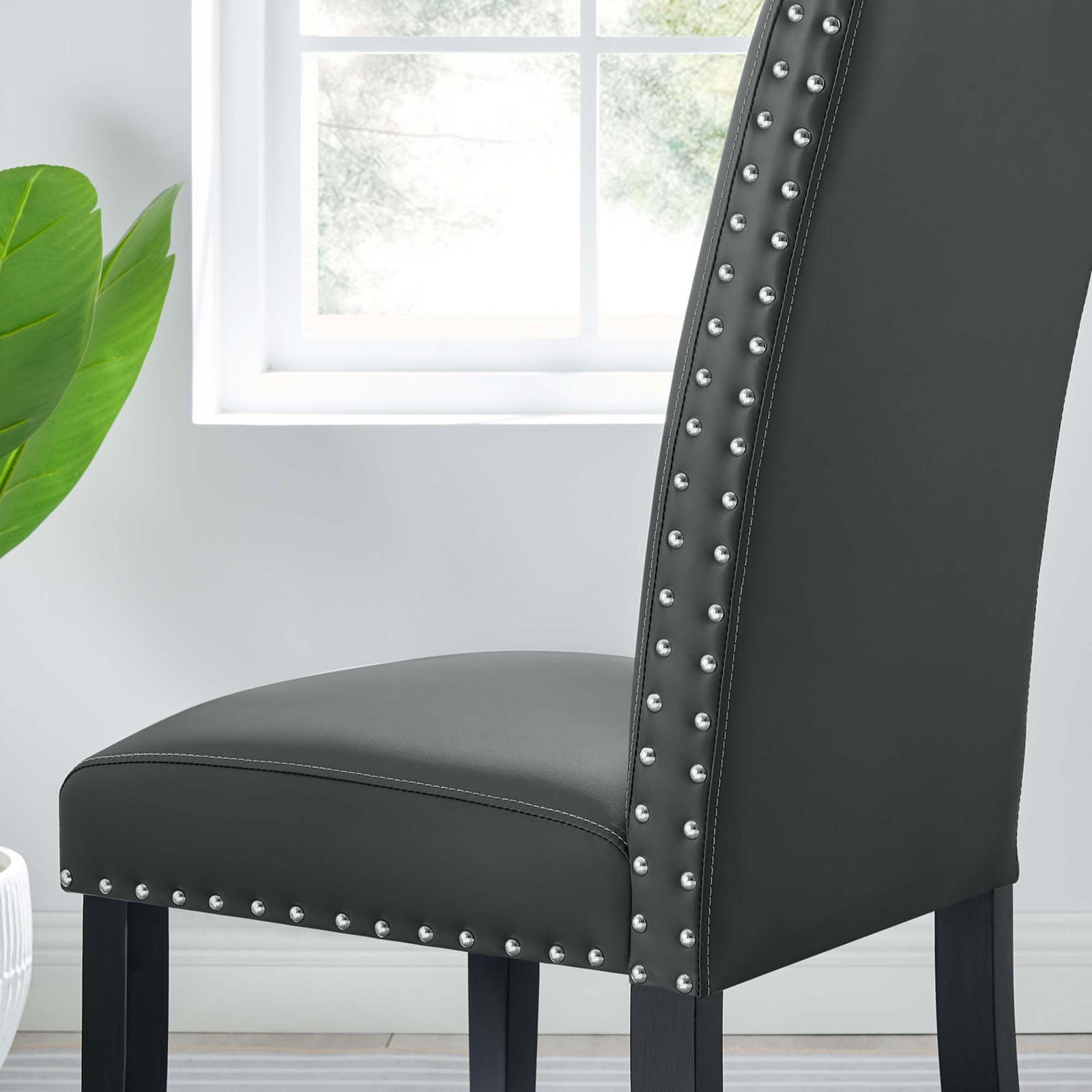 Gray faux leather dining chair by the window highlighting nailhead trim and tailored upholstery details || EEI-1491-GRY || detail_room