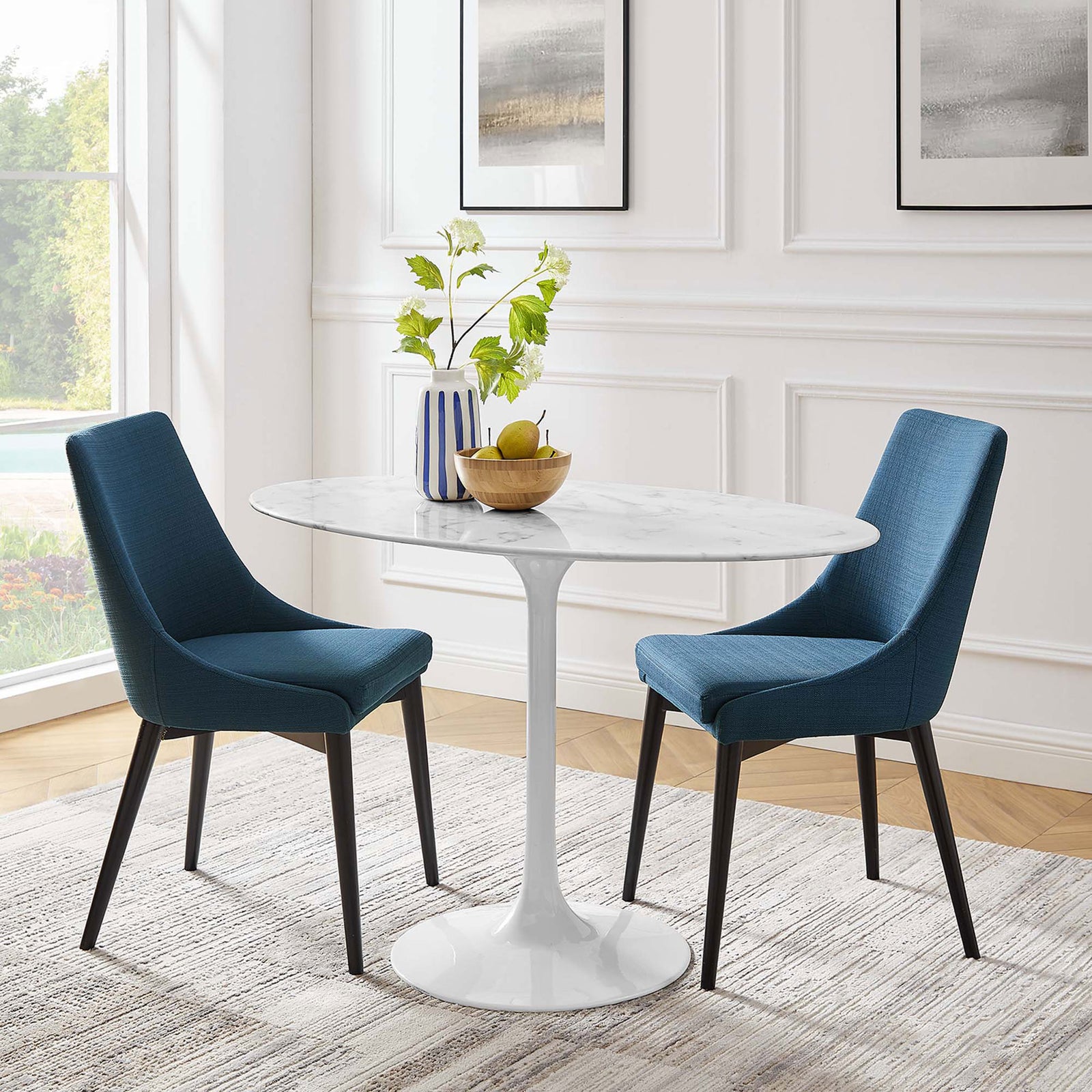 Oval faux marble dining table anchors a bright white dining room with plush blue chairs and greenery || EEI-2021-WHI || front_room