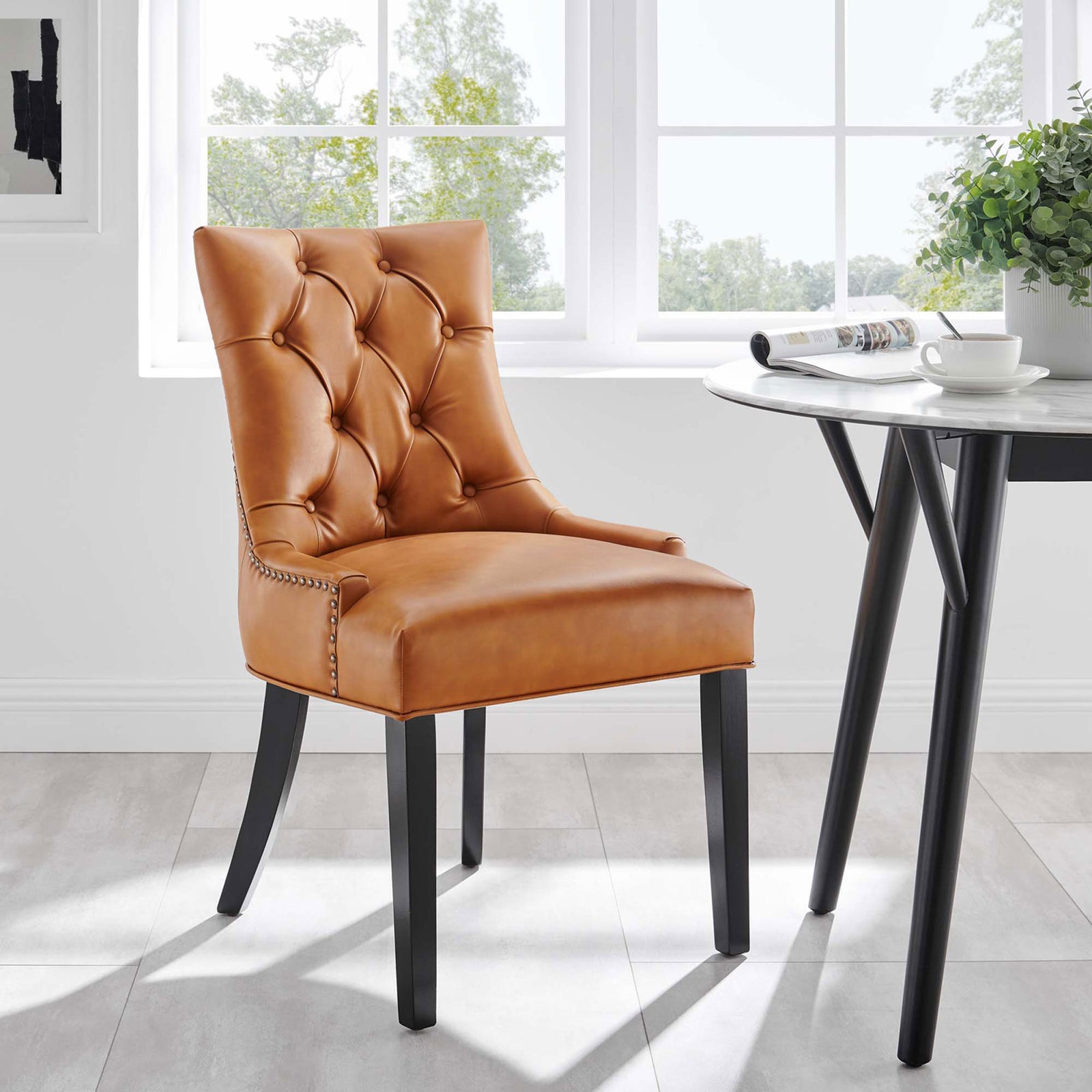 Tan tufted vegan leather dining chair with black legs beside a modern round dining table || EEI-2222-TAN || front_angle_room