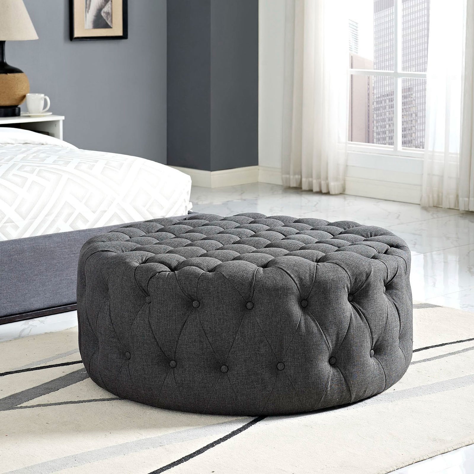 Plush gray ottoman adding upholstered comfort at the foot of a modern, light-filled bed || EEI-2225-GRY || front_angle_room
