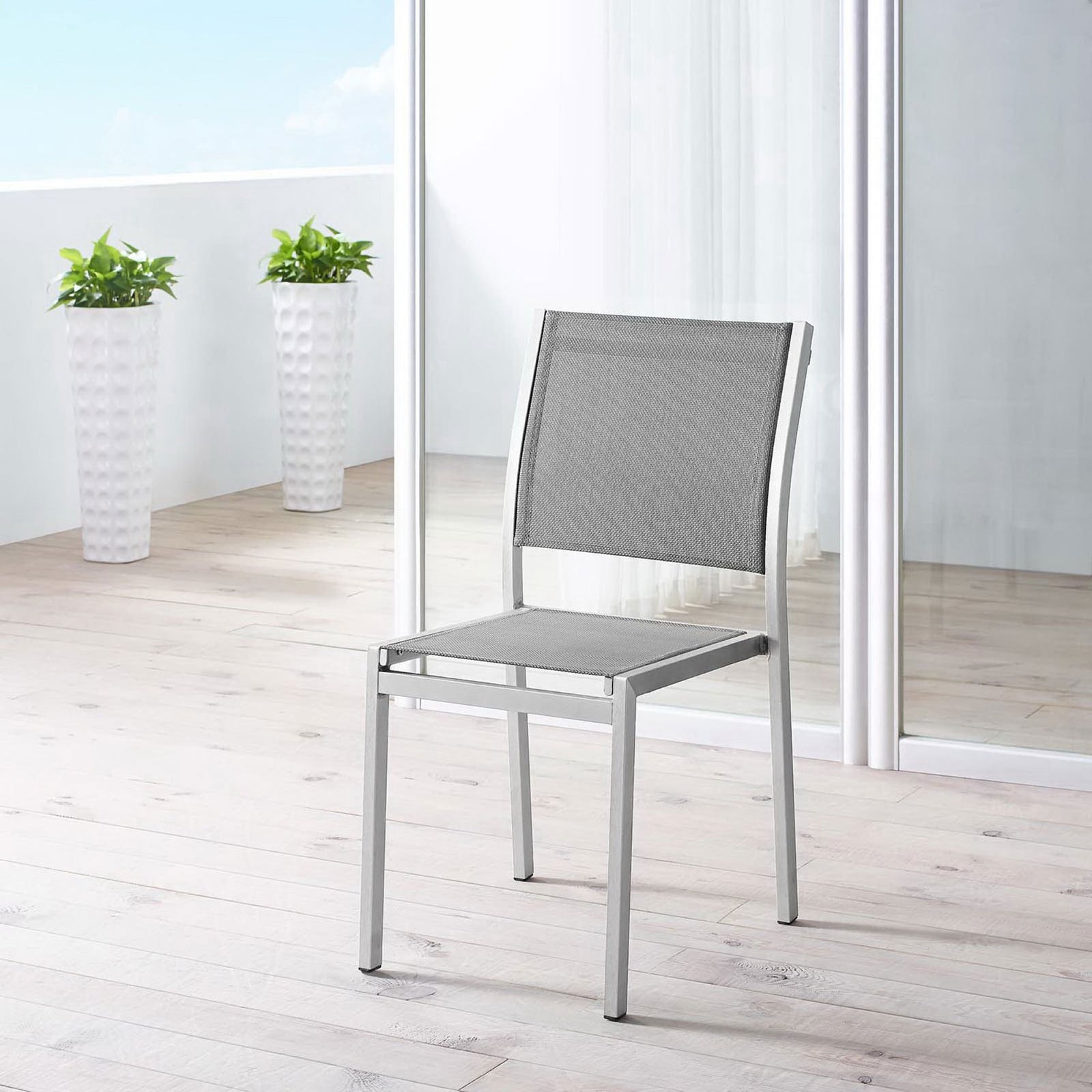 Gray mesh Shore side chair brings airy style to a bright balcony patio setting. || EEI-2259-SLV-GRY || front_angle_room