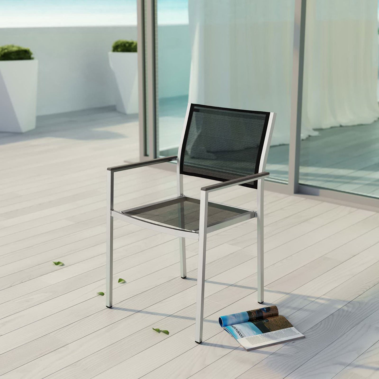 Black mesh Shore armchair adds modern comfort to a bright oceanside patio deck. || EEI-2272-SLV-BLK || front_angle_room