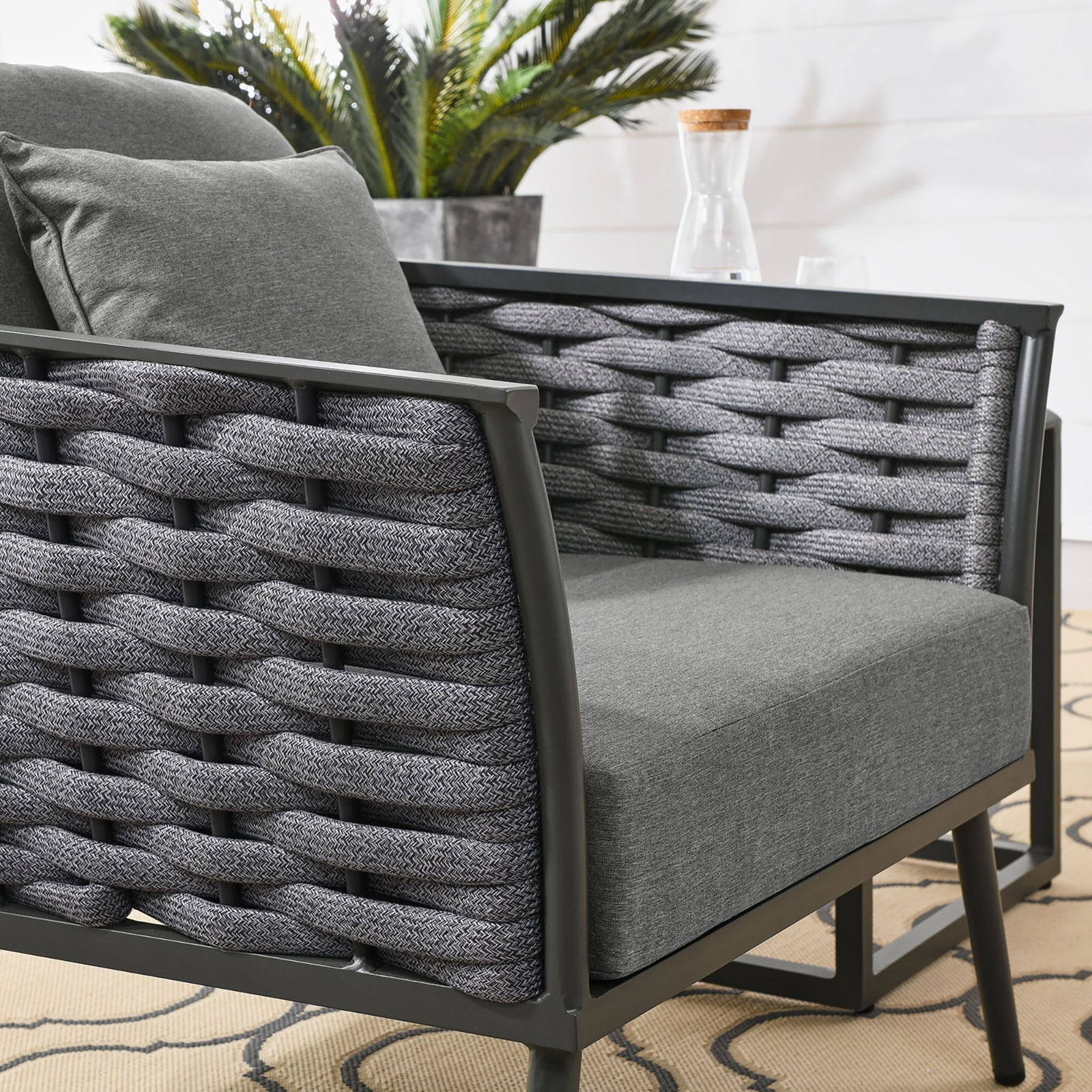 Textured gray rope weave and plush cushions of the Stance outdoor armchair on the patio || EEI-3054-GRY-CHA || detail_room