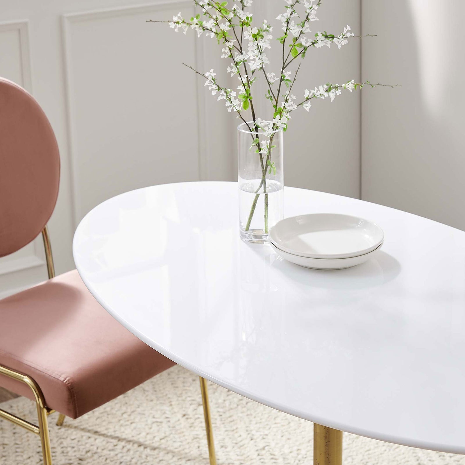 Glossy white tabletop styled with a simple plate and tall floral arrangement on a neutral rug. || EEI-3215-GLD-WHI || detail_room