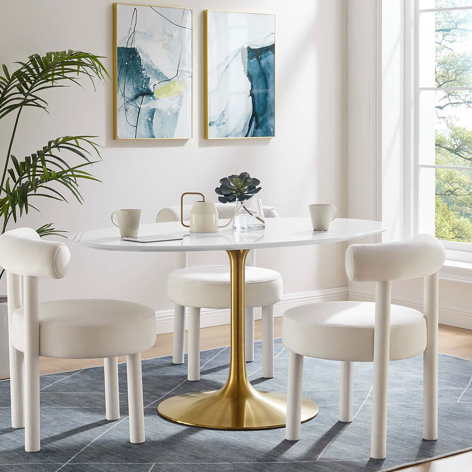 White oval pedestal dining table with gold base paired with plush white chairs in a sunlit dining room. || EEI-3254-GLD-WHI || front_room