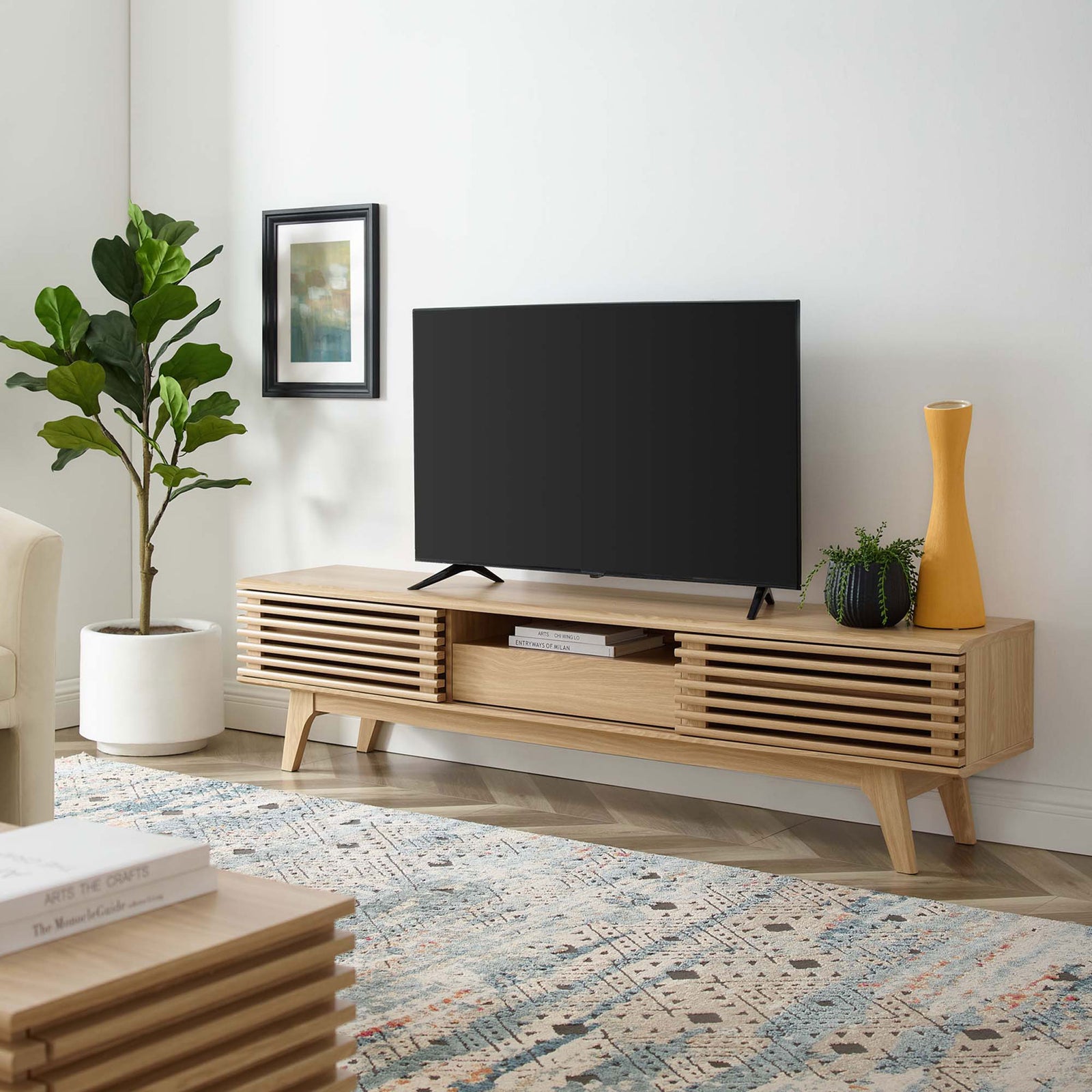 Oak TV stand styled in a bright living room with TV and decorative accents || EEI-3305-OAK || front_angle_room