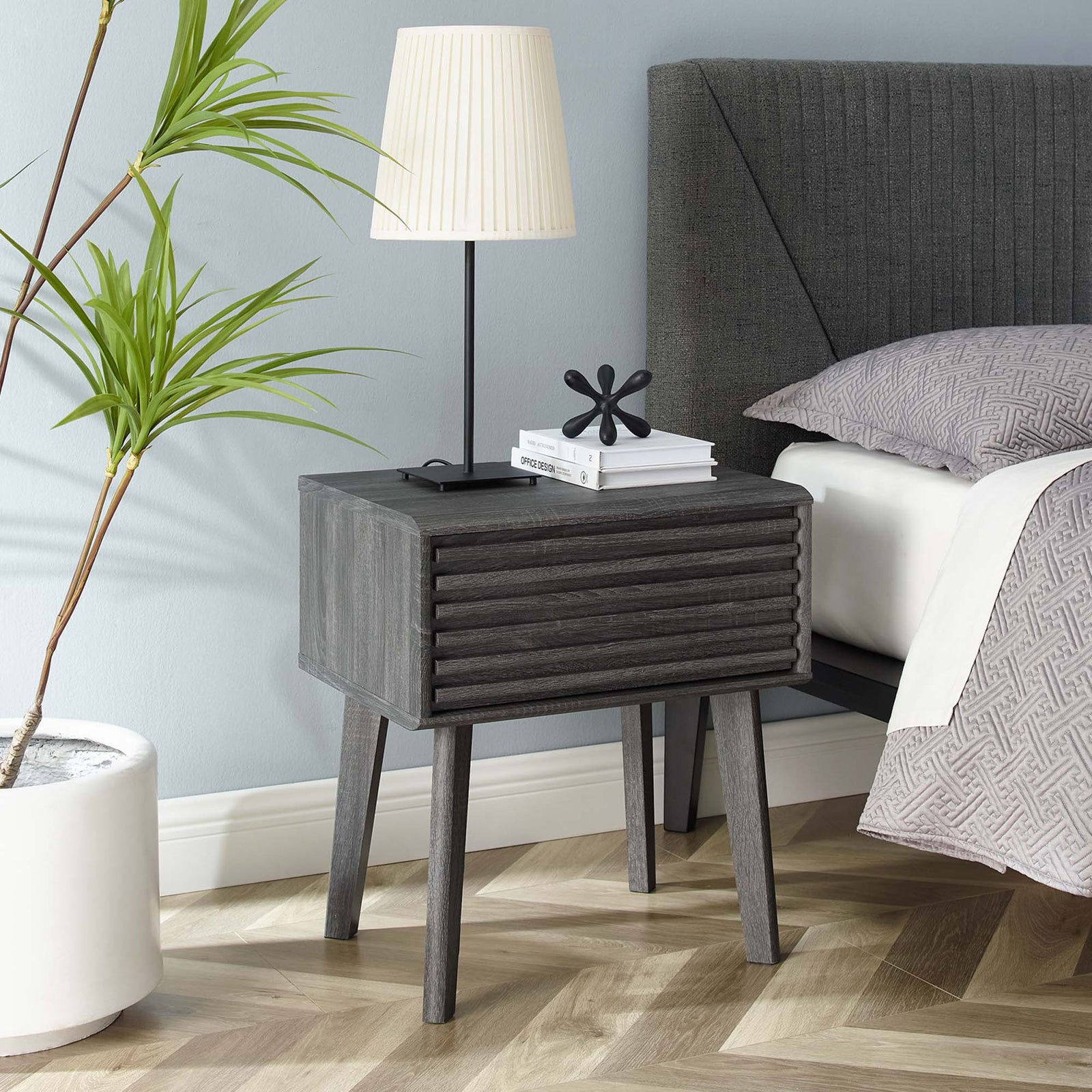 Charcoal mid-century nightstand beside bed with lamp and decor on top || EEI-3345-CHA || front_angle_room