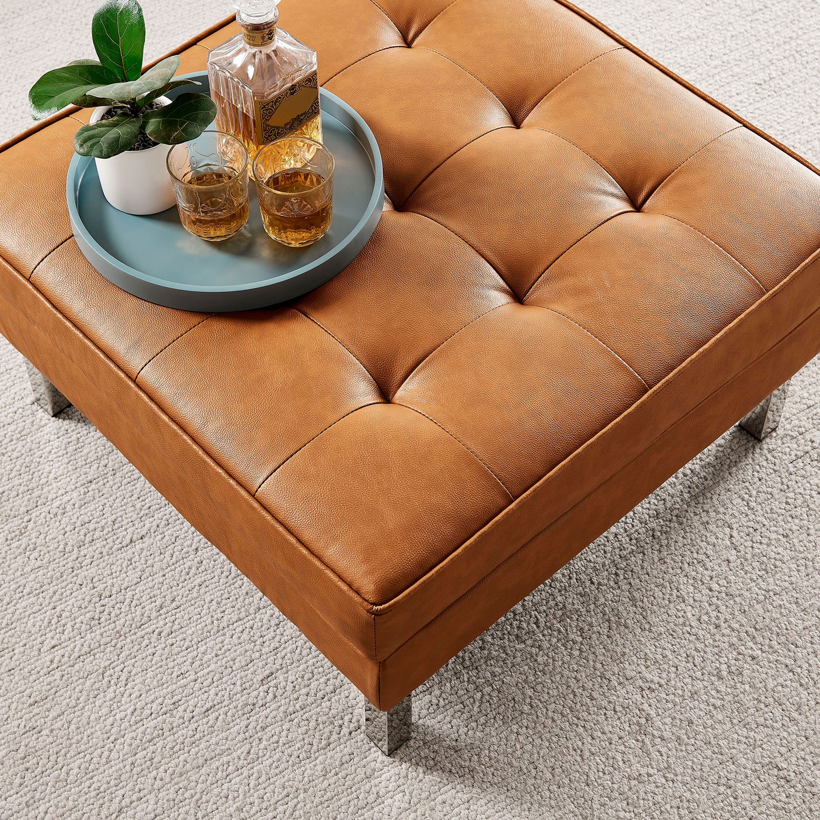 Tan tufted ottoman styled with a tray, plant, and drinks on a soft neutral area rug || EEI-3394-SLV-TAN || detail_room