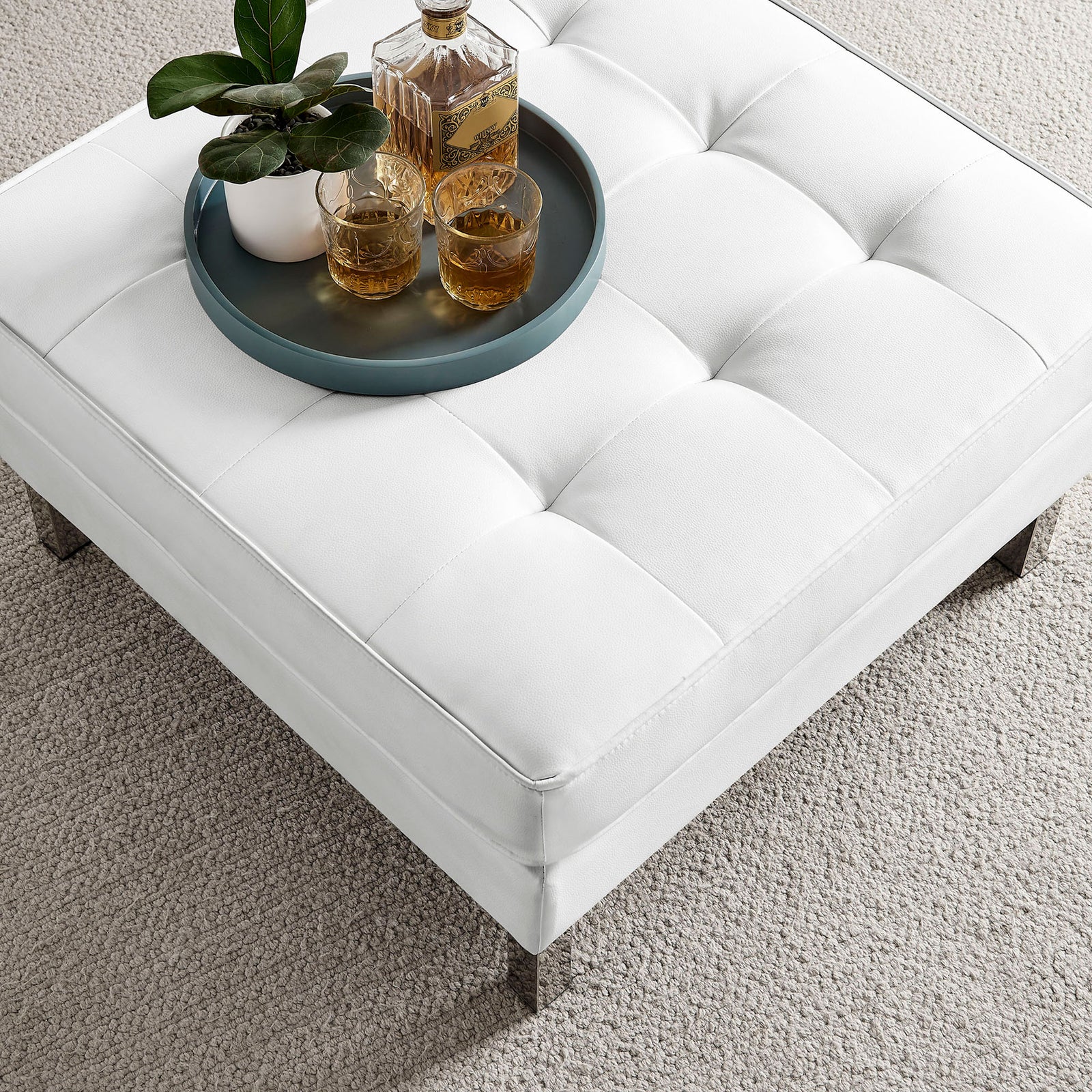 Square tufted ottoman in white vegan leather doubling as a chic coffee table on soft carpet || EEI-3394-SLV-WHI || top_angle_room