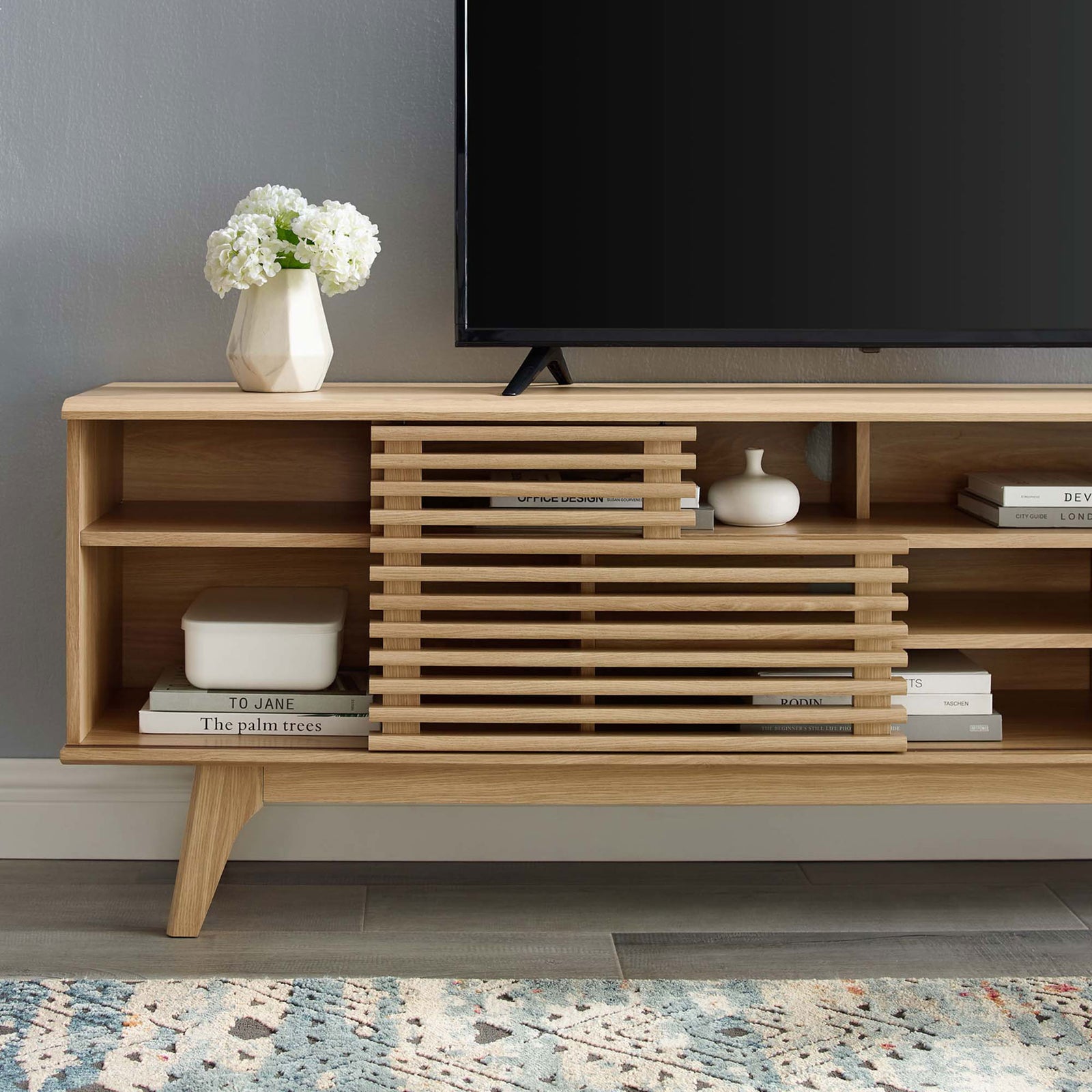 Oak media console shelving styled with books and decor beside a TV in a contemporary room || EEI-3433-OAK || detail_room