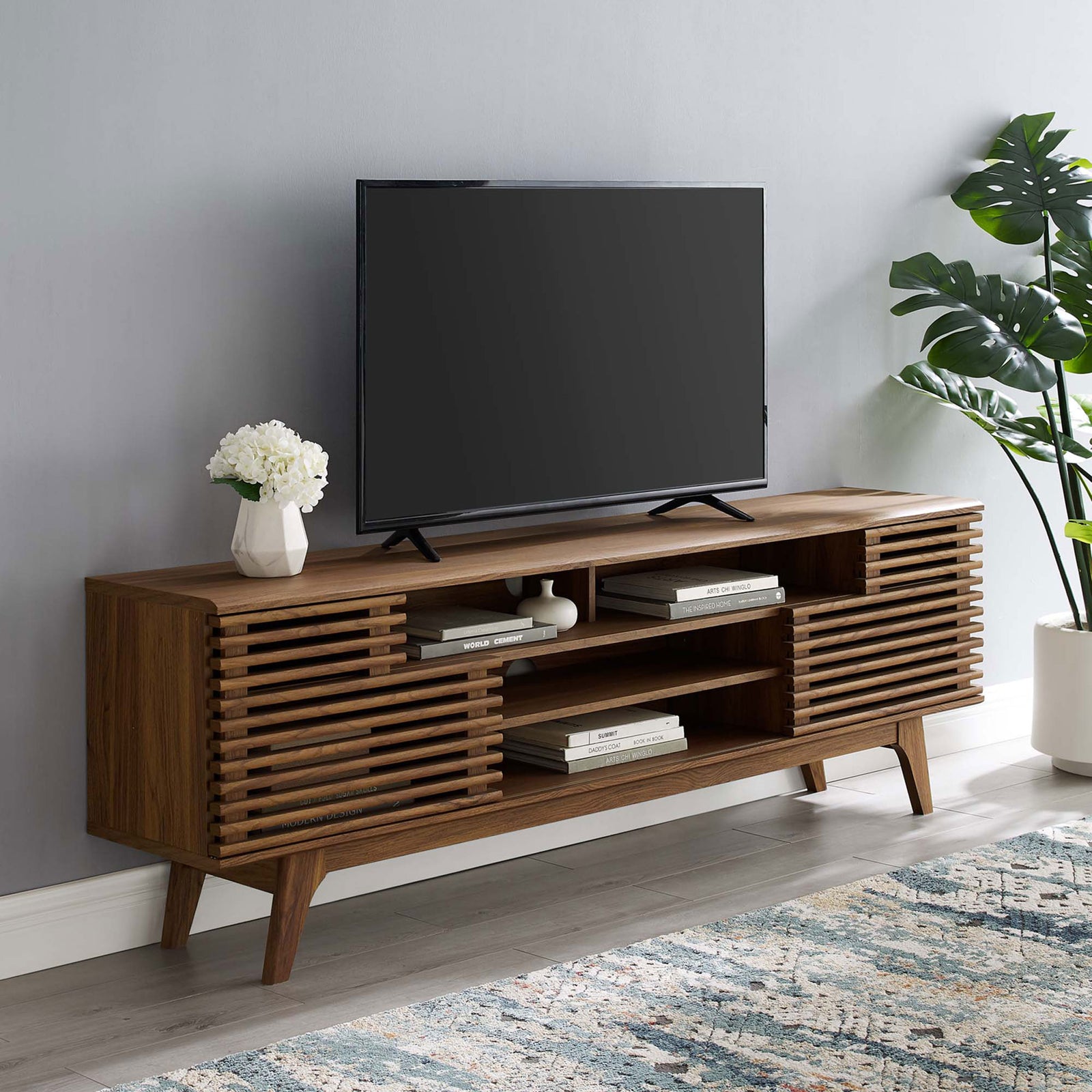 Walnut media console in a styled living room with TV, rug, and plant decor || EEI-3433-WAL || front_angle_room