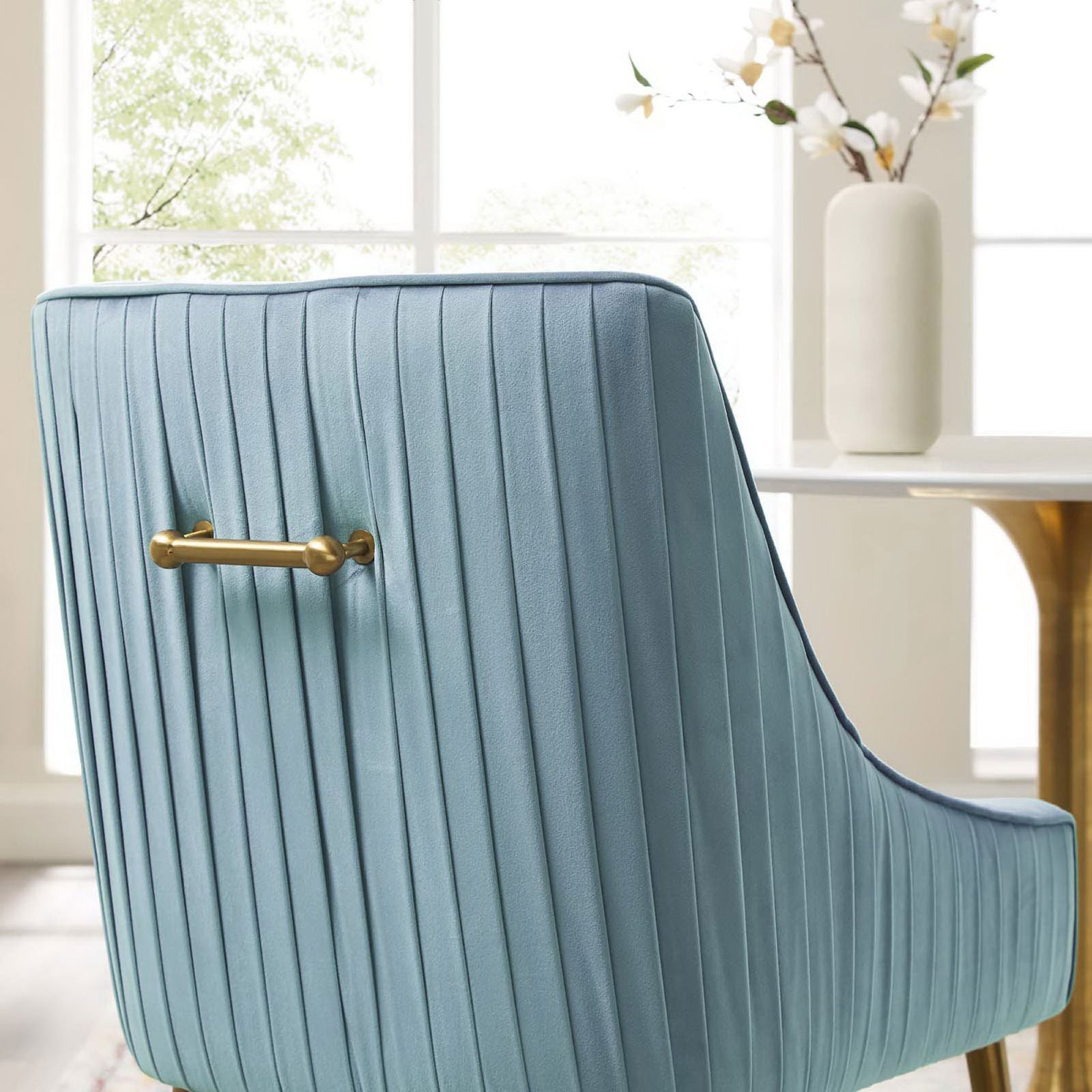 Close-up of pleated light blue chair back with sleek brushed gold handle in a bright dining room || EEI-3509-LBU || handle_room