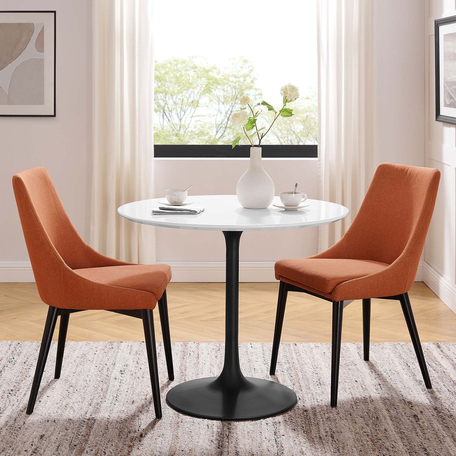 Modern round pedestal table paired with two orange chairs creates an inviting small-space dining set || EEI-3511-BLK-WHI || front_angle_room