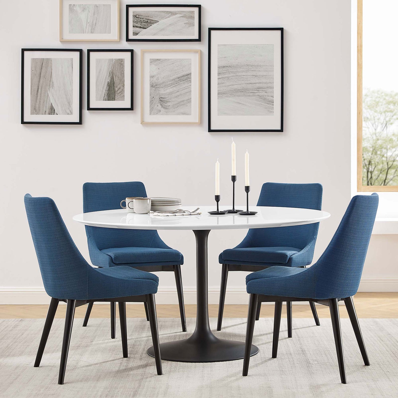 Contemporary dining room with blue upholstered chairs anchored by a sleek round pedestal table || EEI-3523-BLK-WHI || front_angle_room