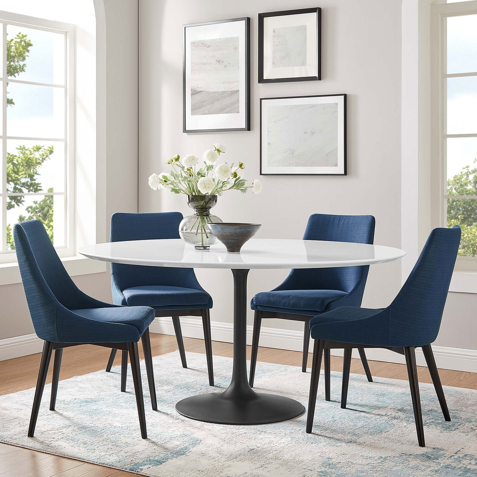 Airy dining room with blue chairs surrounding a large round pedestal table for lively gatherings || EEI-3524-BLK-WHI || front_angle_room