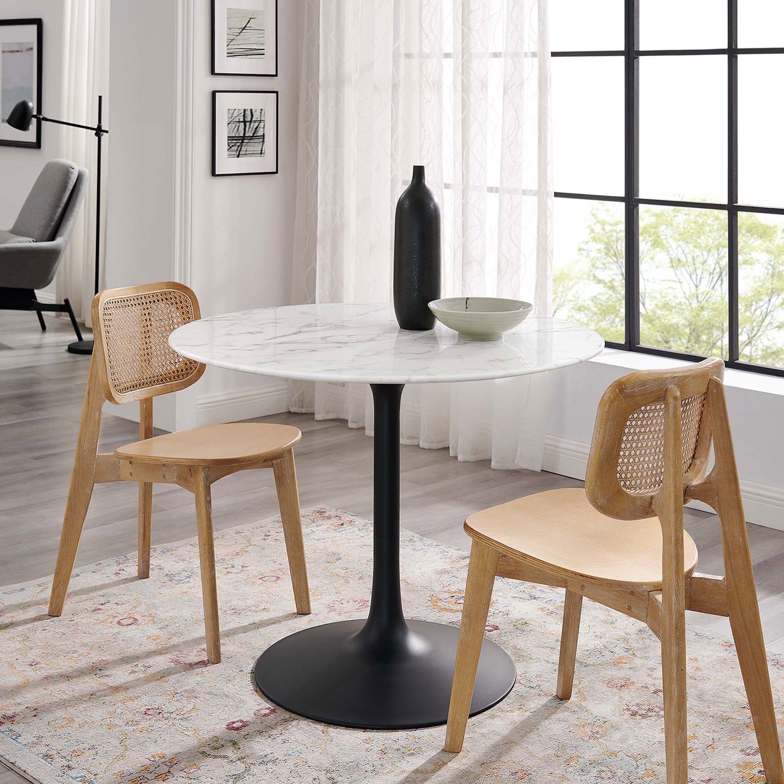 Round faux marble dining table paired with two woven back chairs in a light filled modern room || EEI-3526-BLK-WHI || front_angle_room