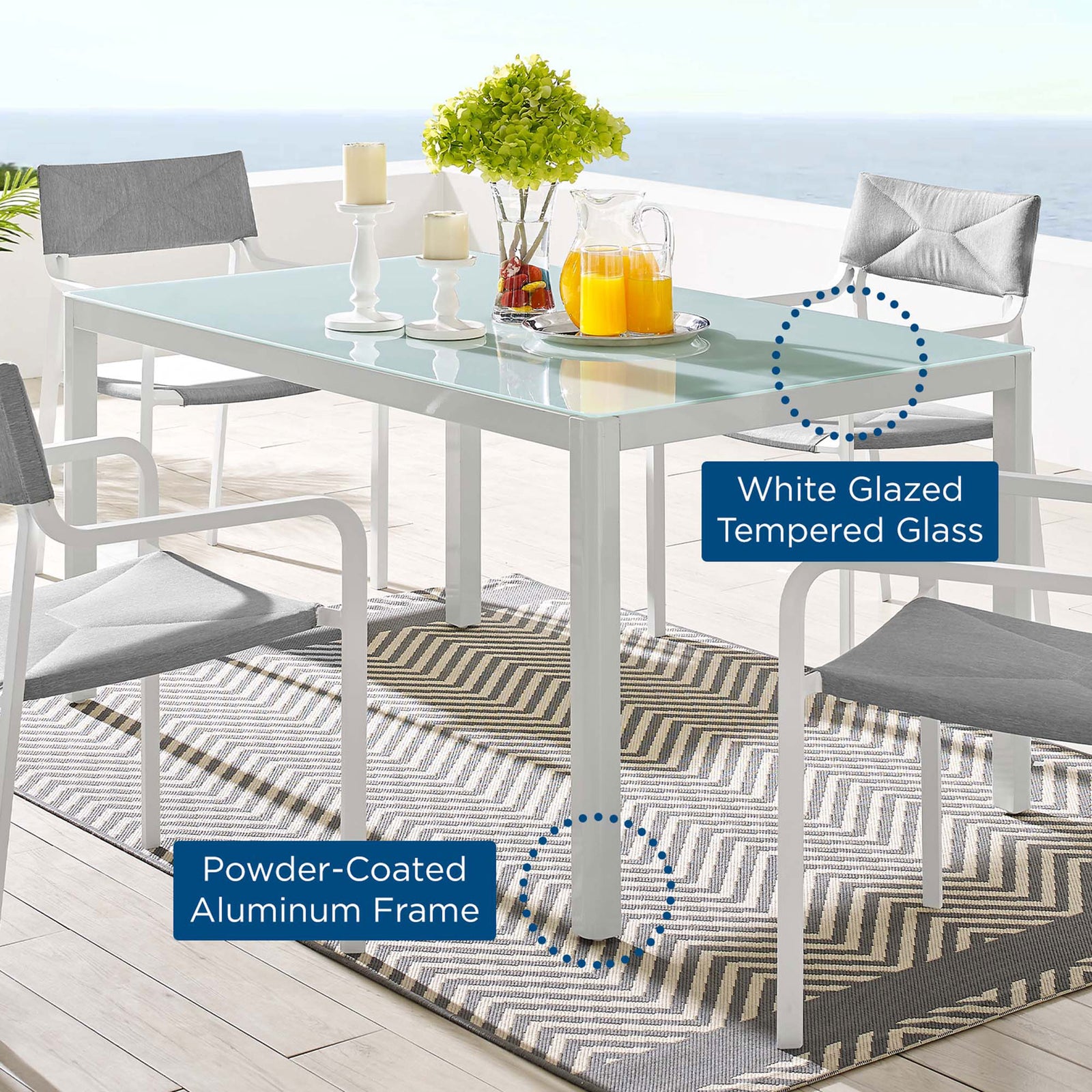Outdoor dining table styled with chairs, rug, and decor highlighting glass top and metal frame || EEI-3576-WHI || callout_room