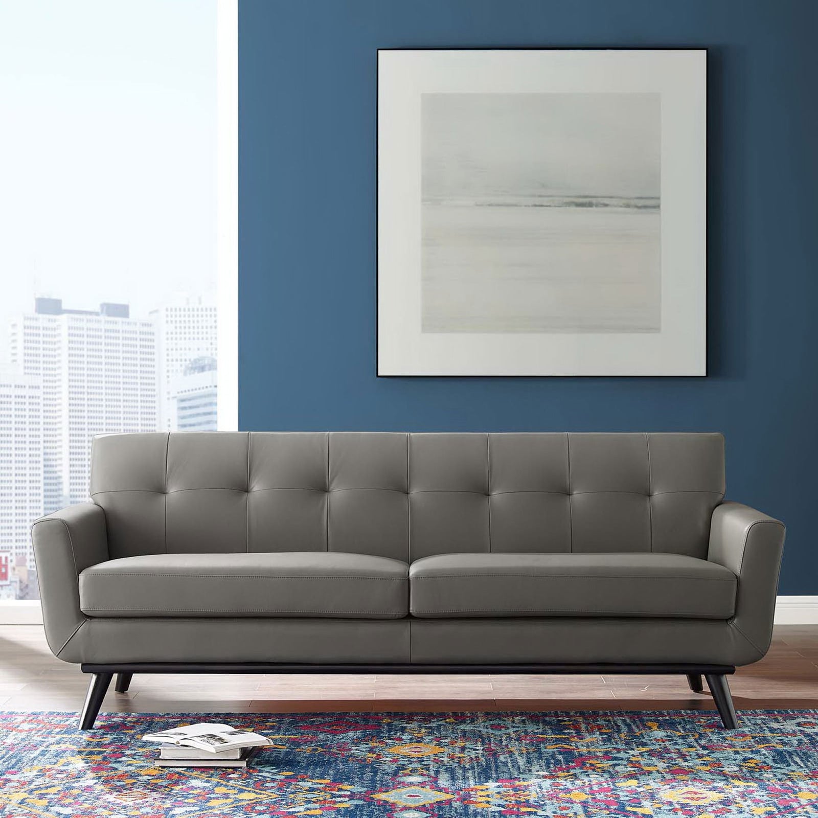 Gray leather sofa styled in a modern living room with blue accent wall, city artwork, and colorful rug || EEI-3733-GRY || front_room