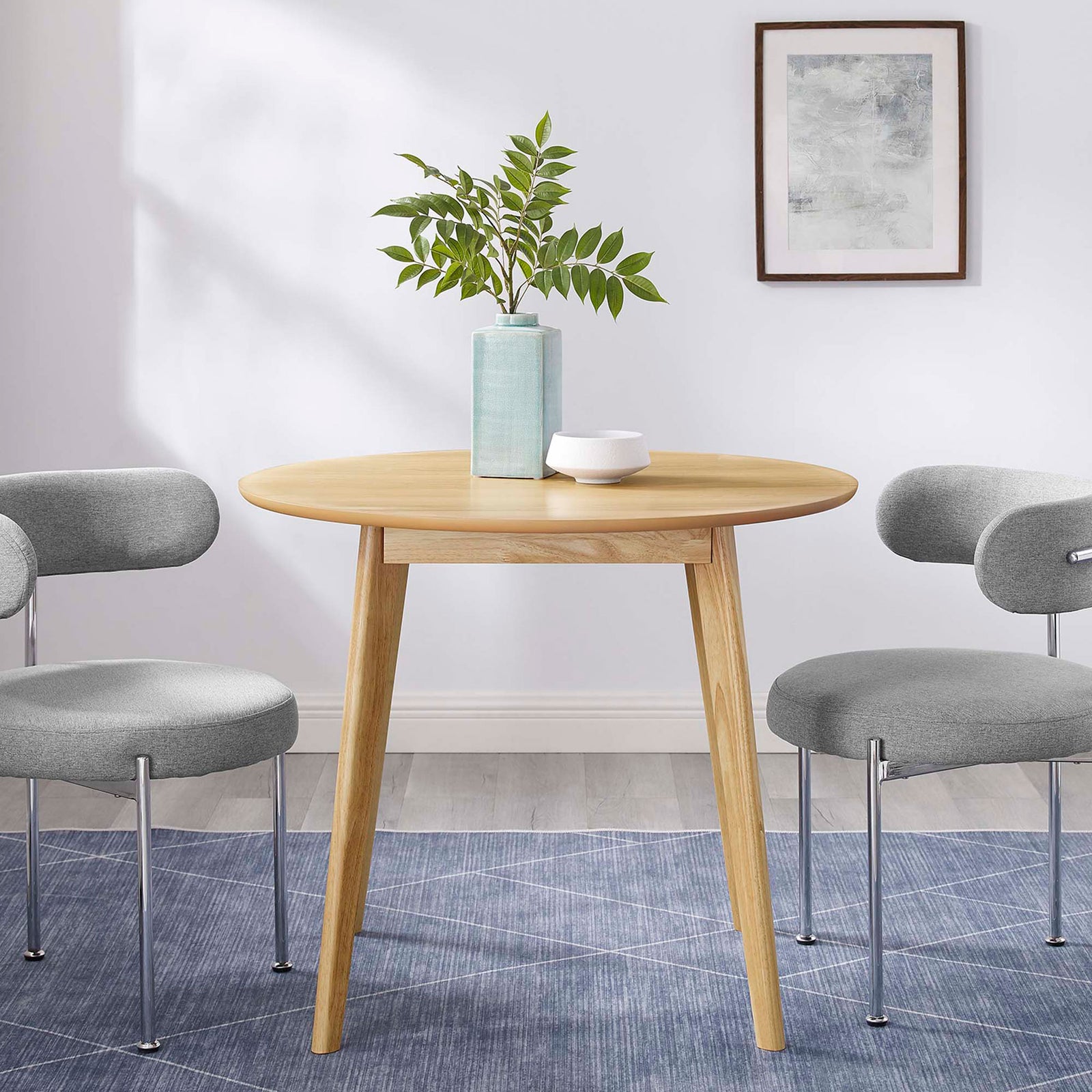 Round oak dining table framed by gray chairs, perfect centerpiece for a contemporary dining room || EEI-3749-OAK || front_room