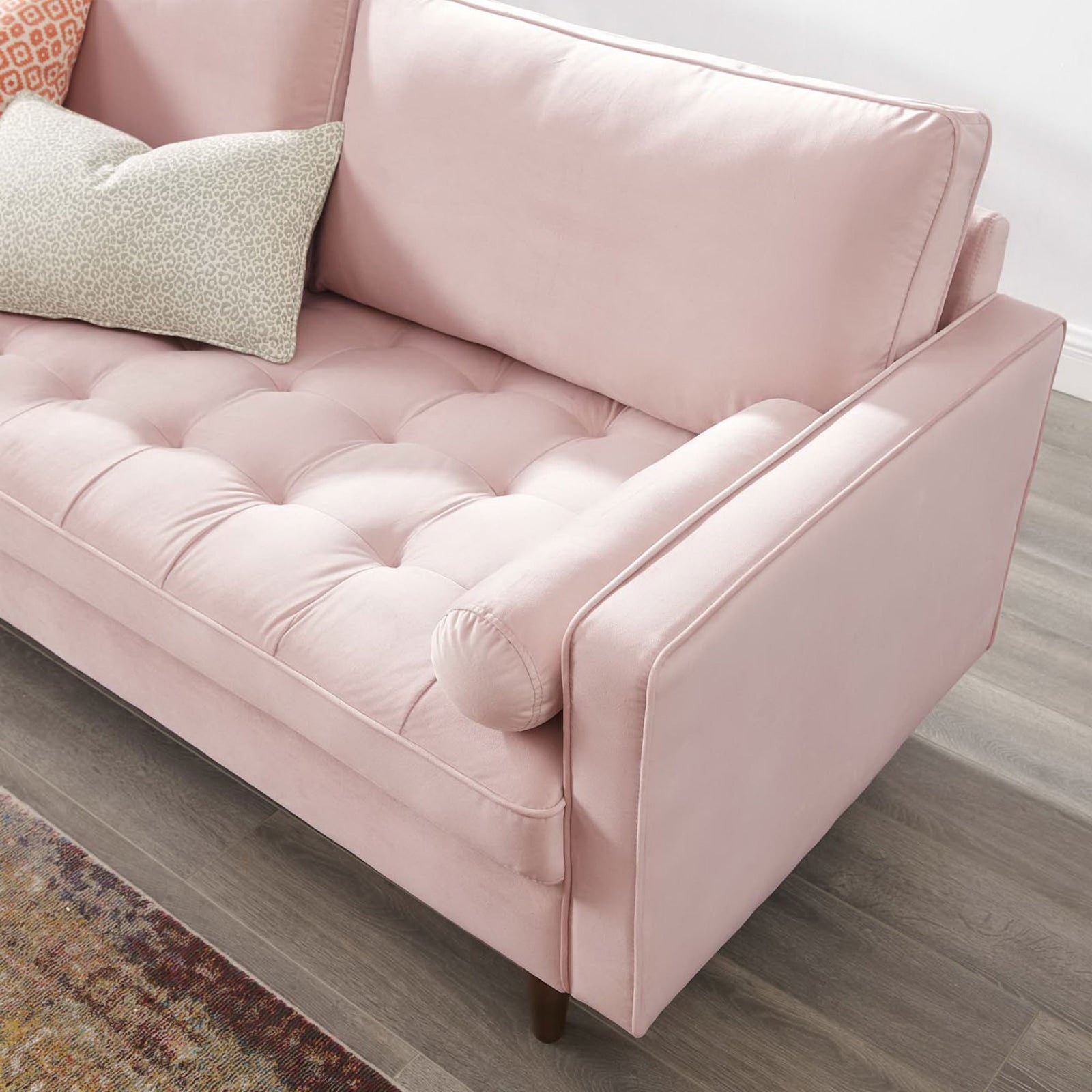 Valour pink velvet sofa arm showcasing tufted seat, bolster pillow, and mid-century wood leg in a styled living room || EEI-3764-PNK || detail_room