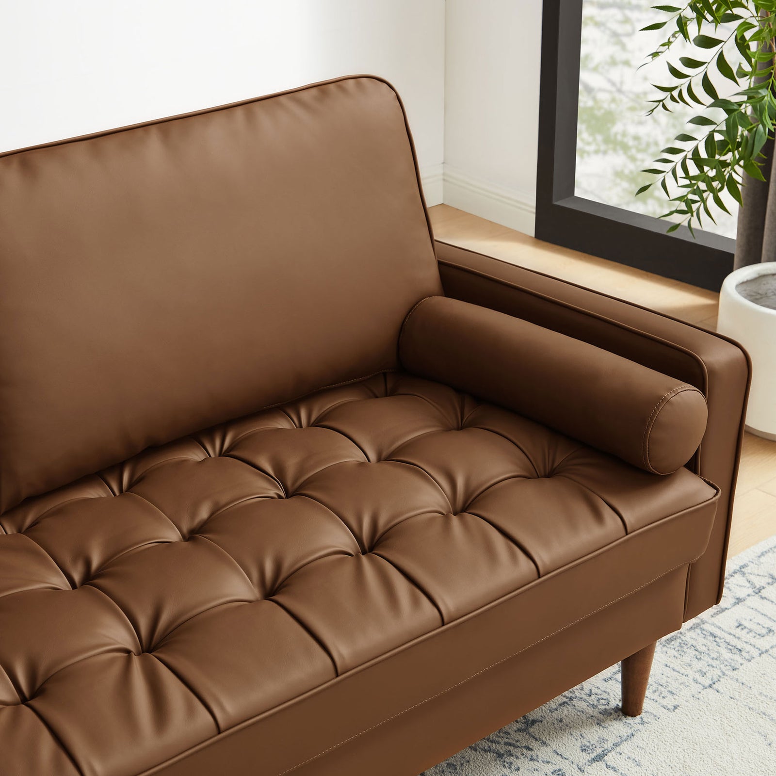 Brown vegan leather Valour sofa detail with bolster pillow, tufted seat, and modern living room decor || EEI-3765-BRN || detail_room