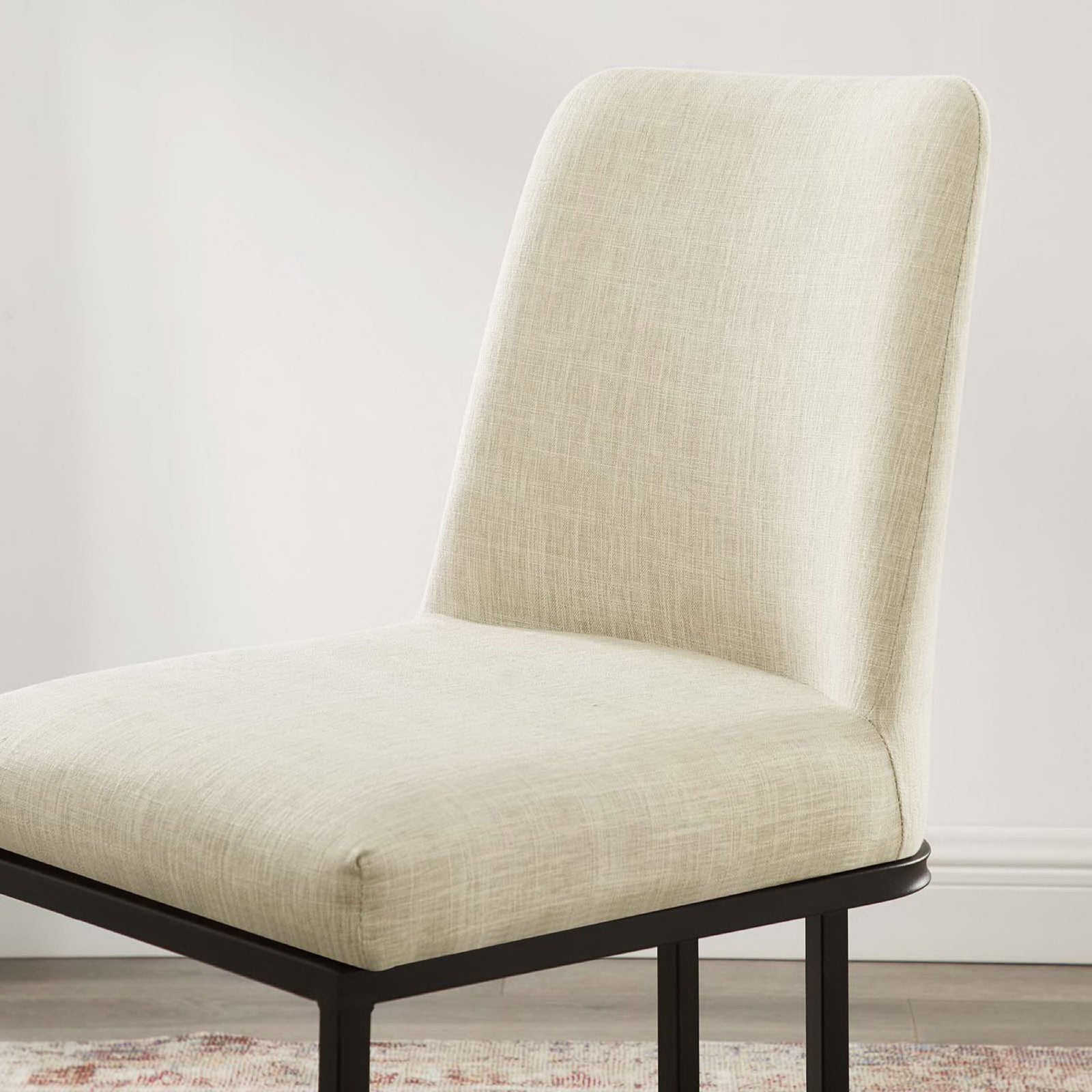 Beige fabric dining chair in a bright dining room showing softly curved back and smooth upholstery || EEI-3811-BLK-BEI || detail_room