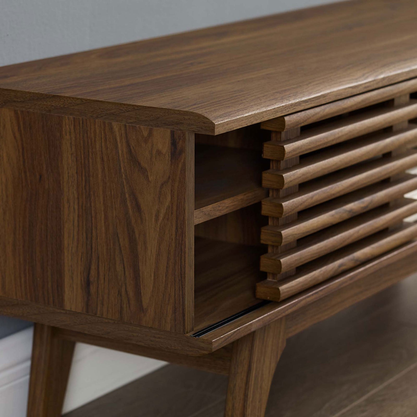 Corner detail of the TV console styled in a living room with wall and floor. || EEI-3837-WAL || detail_room