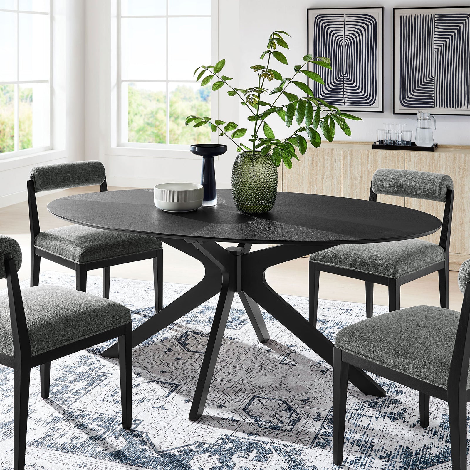 Black oval dining table arranged in a modern dining room with gray chairs and geometric art || EEI-3849-BLK || front_angle_room