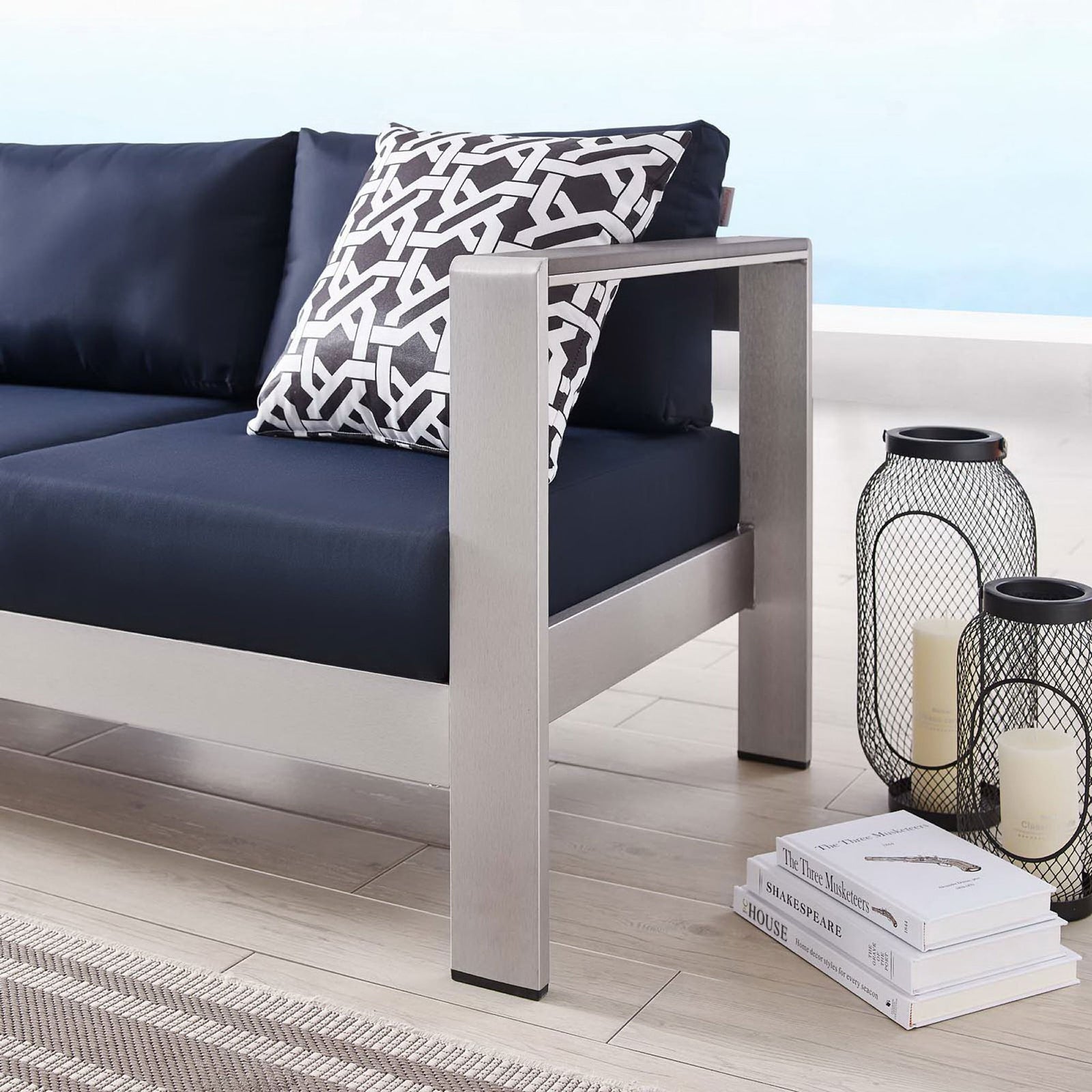 Brushed aluminum arm and deep navy seat pair with lanterns and books for relaxed outdoor lounging || EEI-3917-SLV-NAV || detail_room