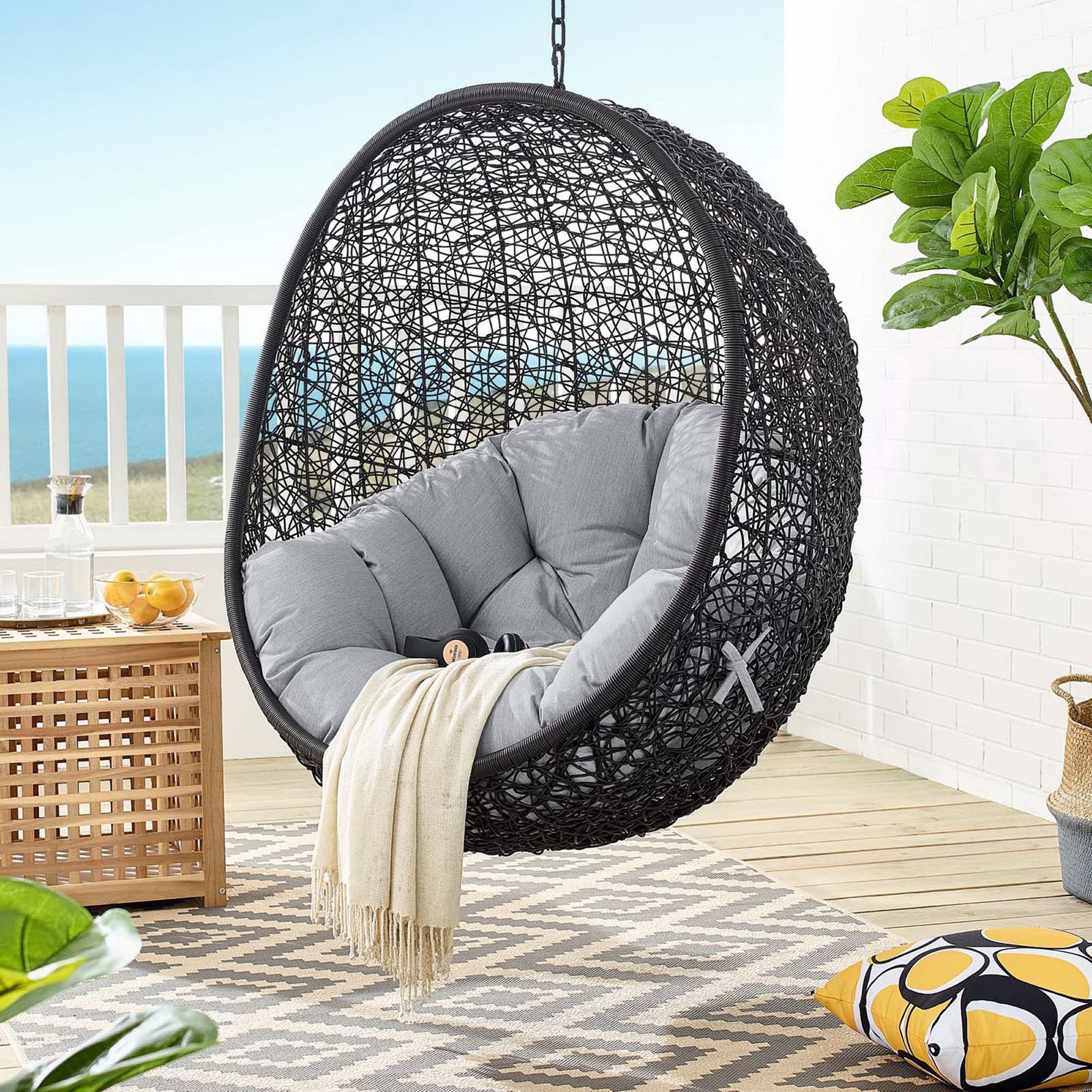 Suspended gray Sunbrella swing chair creating a cozy nook with ocean view and soft breeze || EEI-3943-BLK-GRY || front_angle_partial_room
